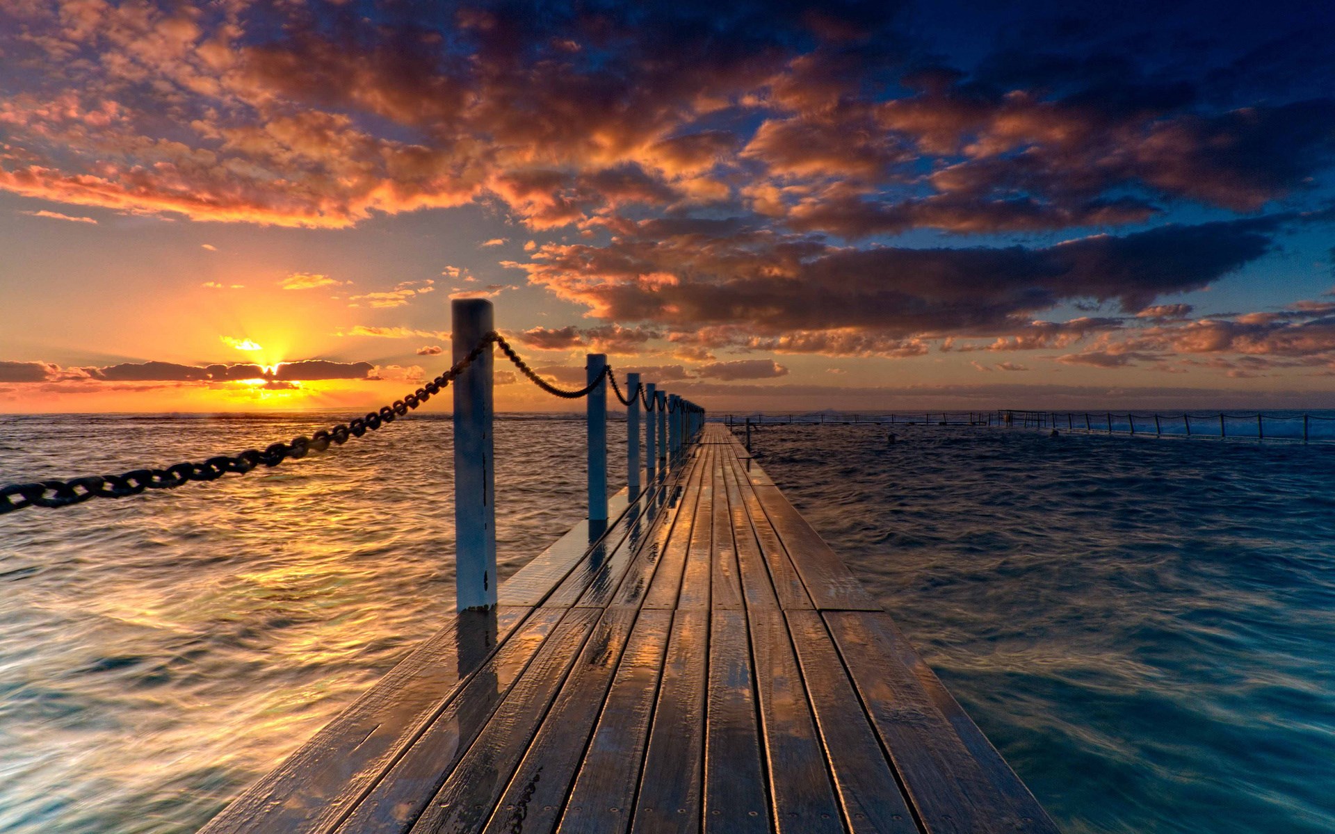 Wooden pier extending into the ocean at sunset HD Wallpaper
