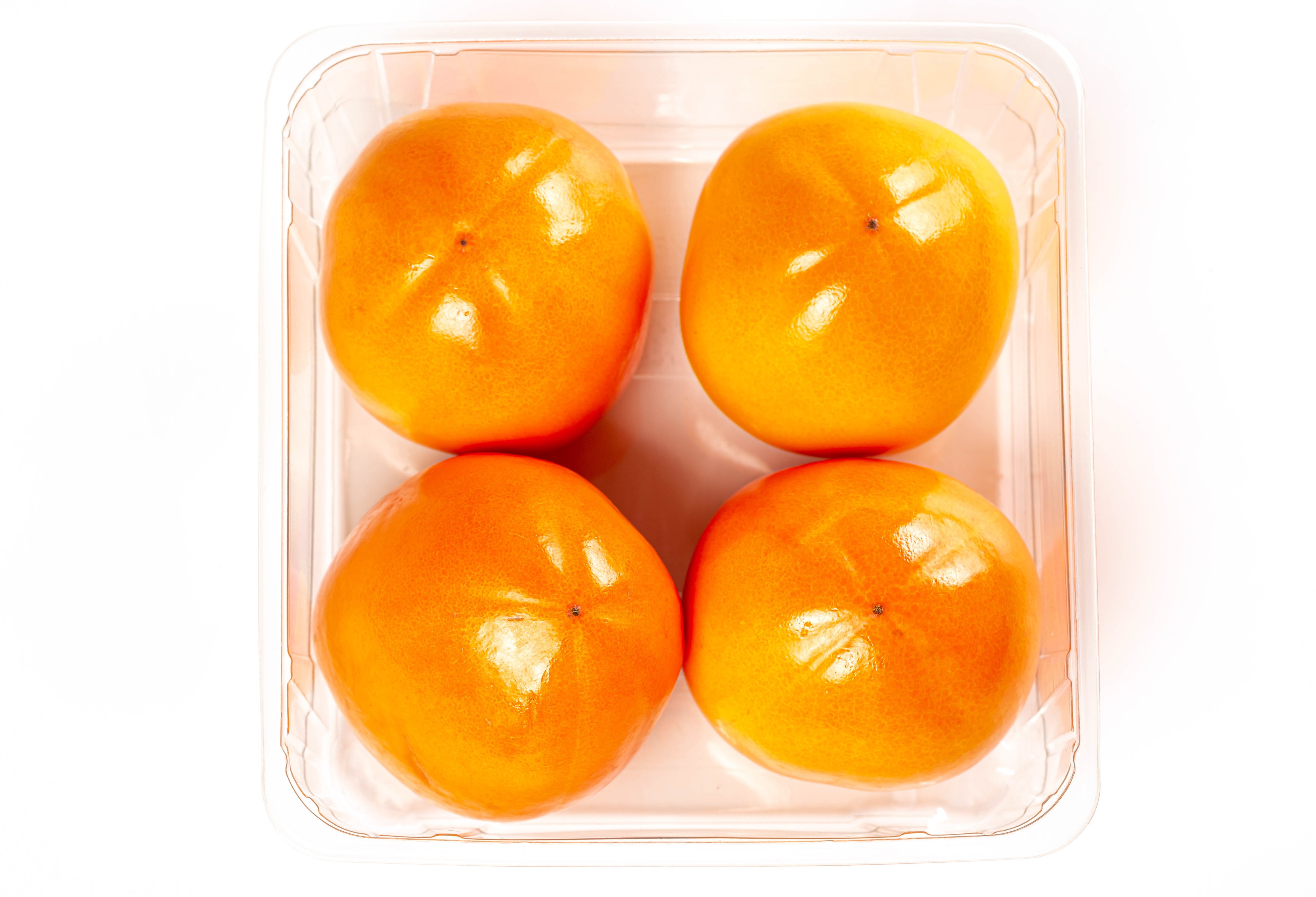 Four persimmons in a plastic container HD Wallpaper