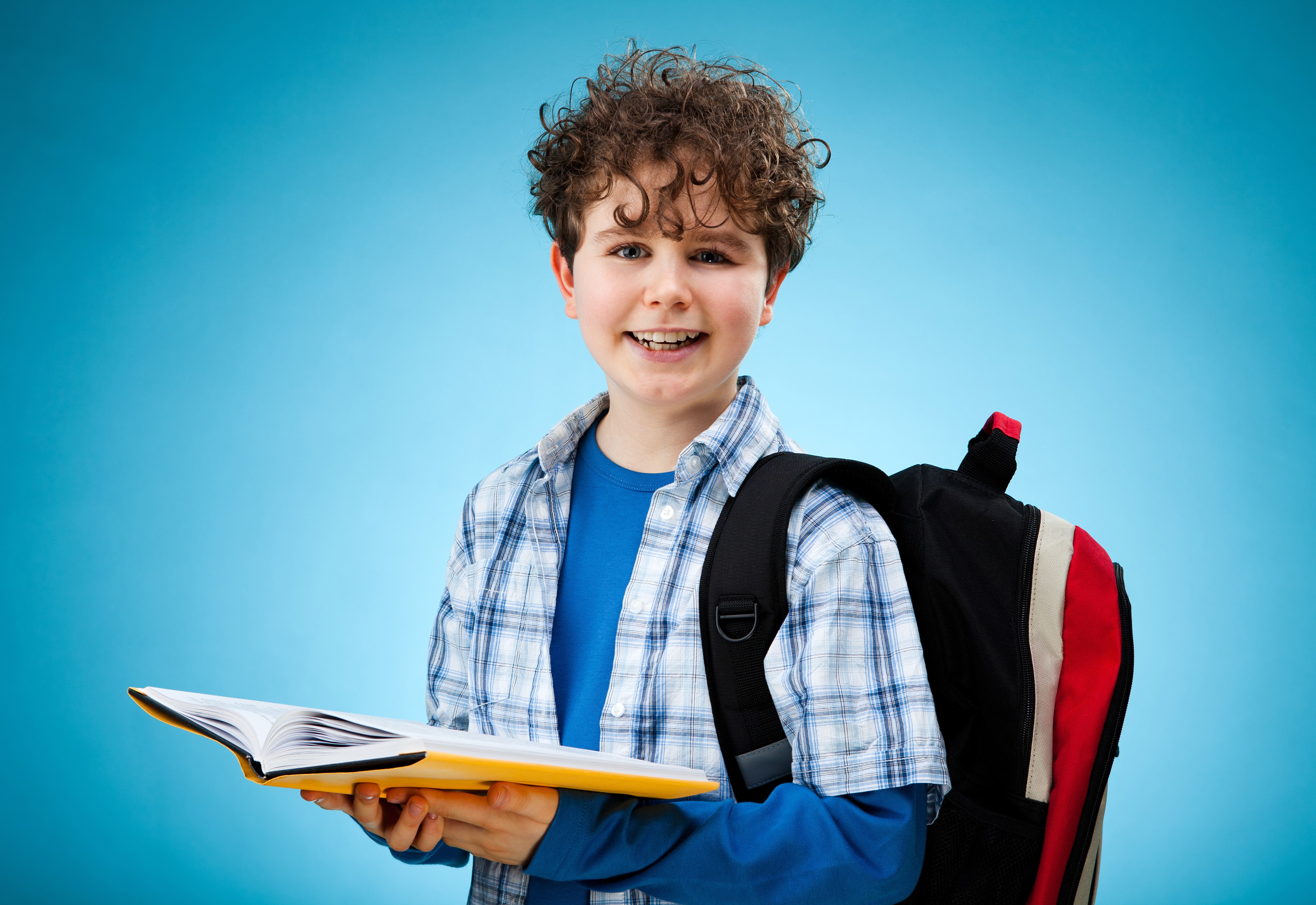 Boy with curly hair holding a book and wearing a backpack HD Wallpaper