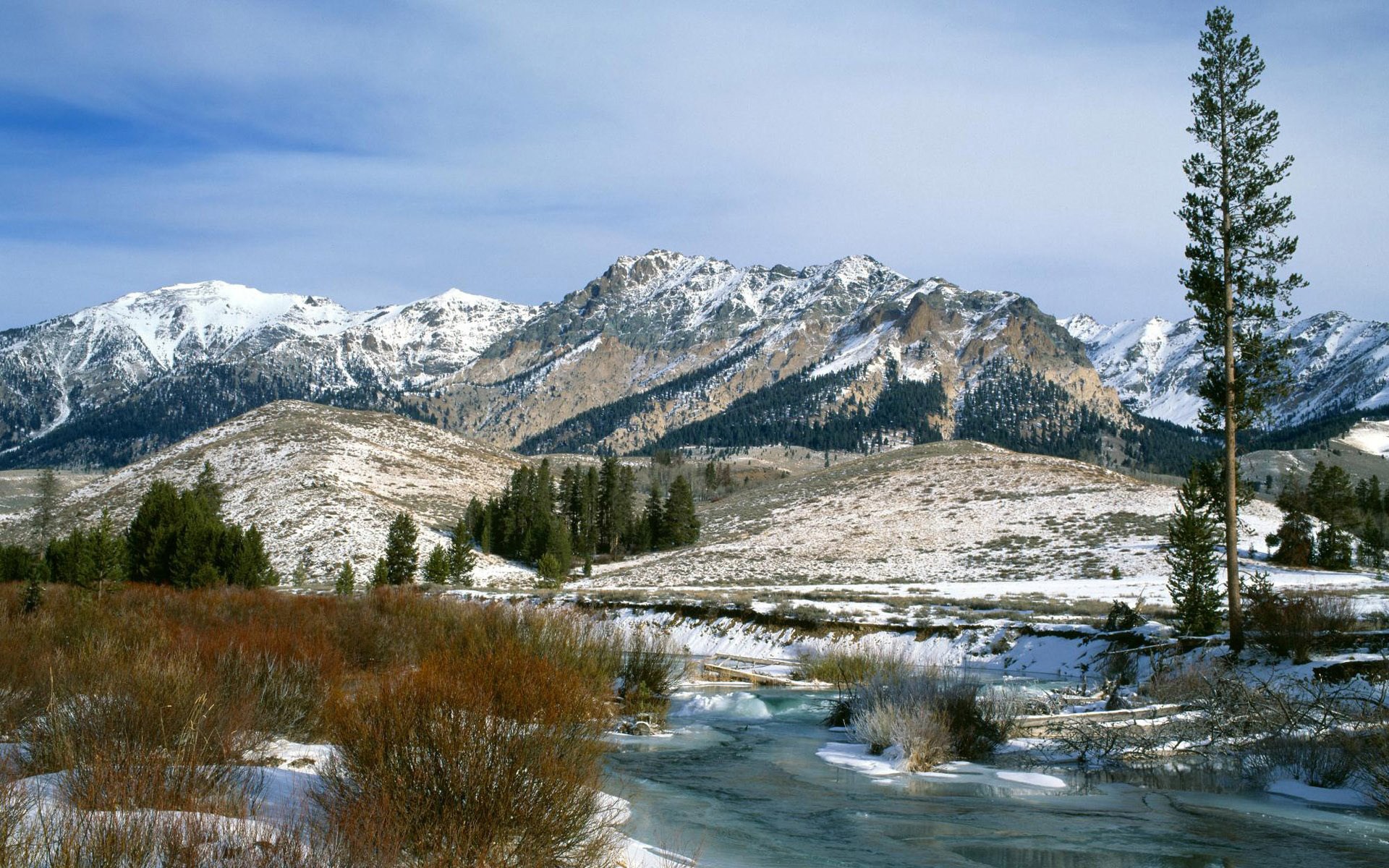 Snow-covered mountains and a partially frozen river in winter HD Wallpaper