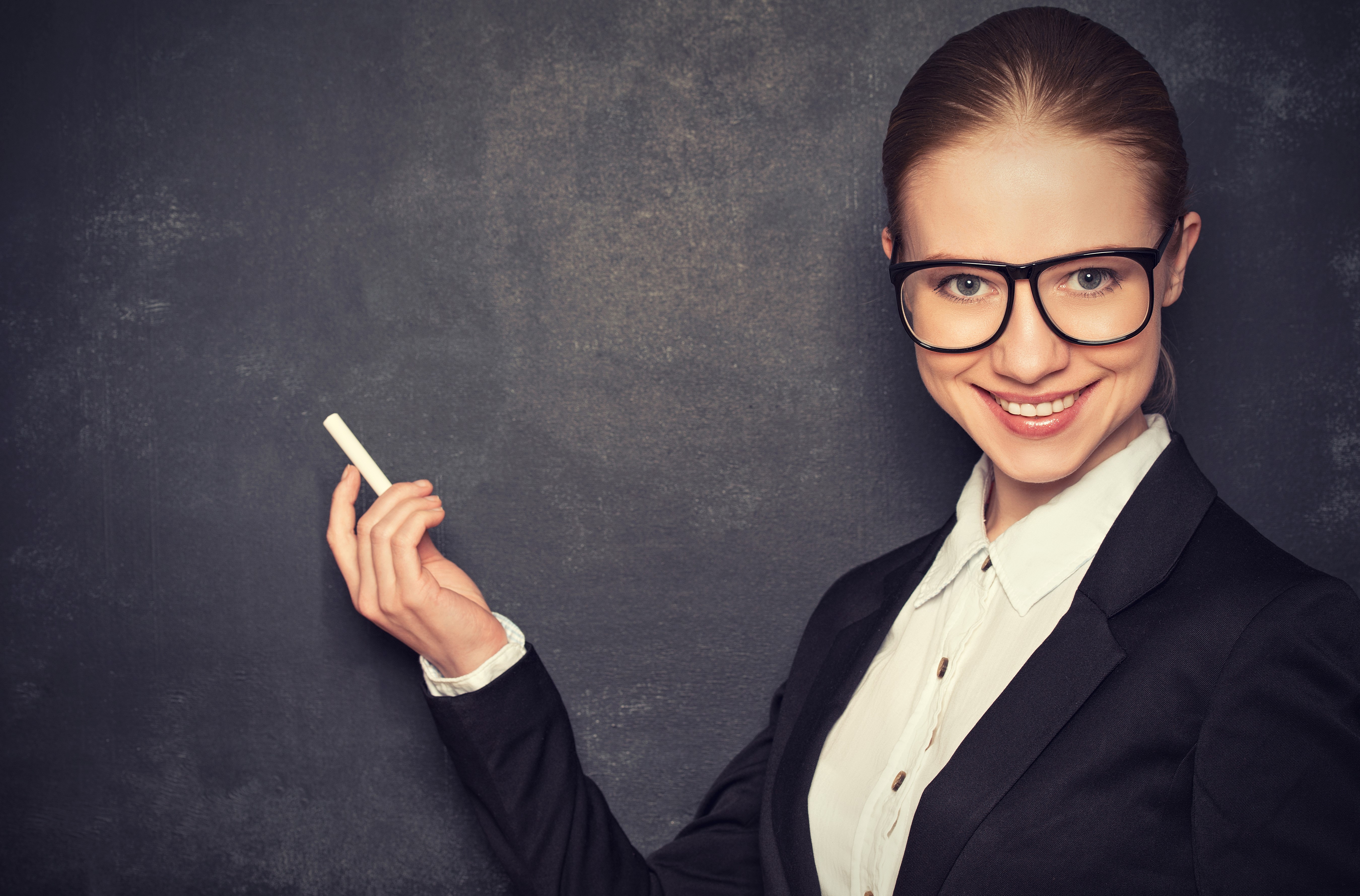 Teacher with glasses holding chalk in front of blackboard HD Wallpaper