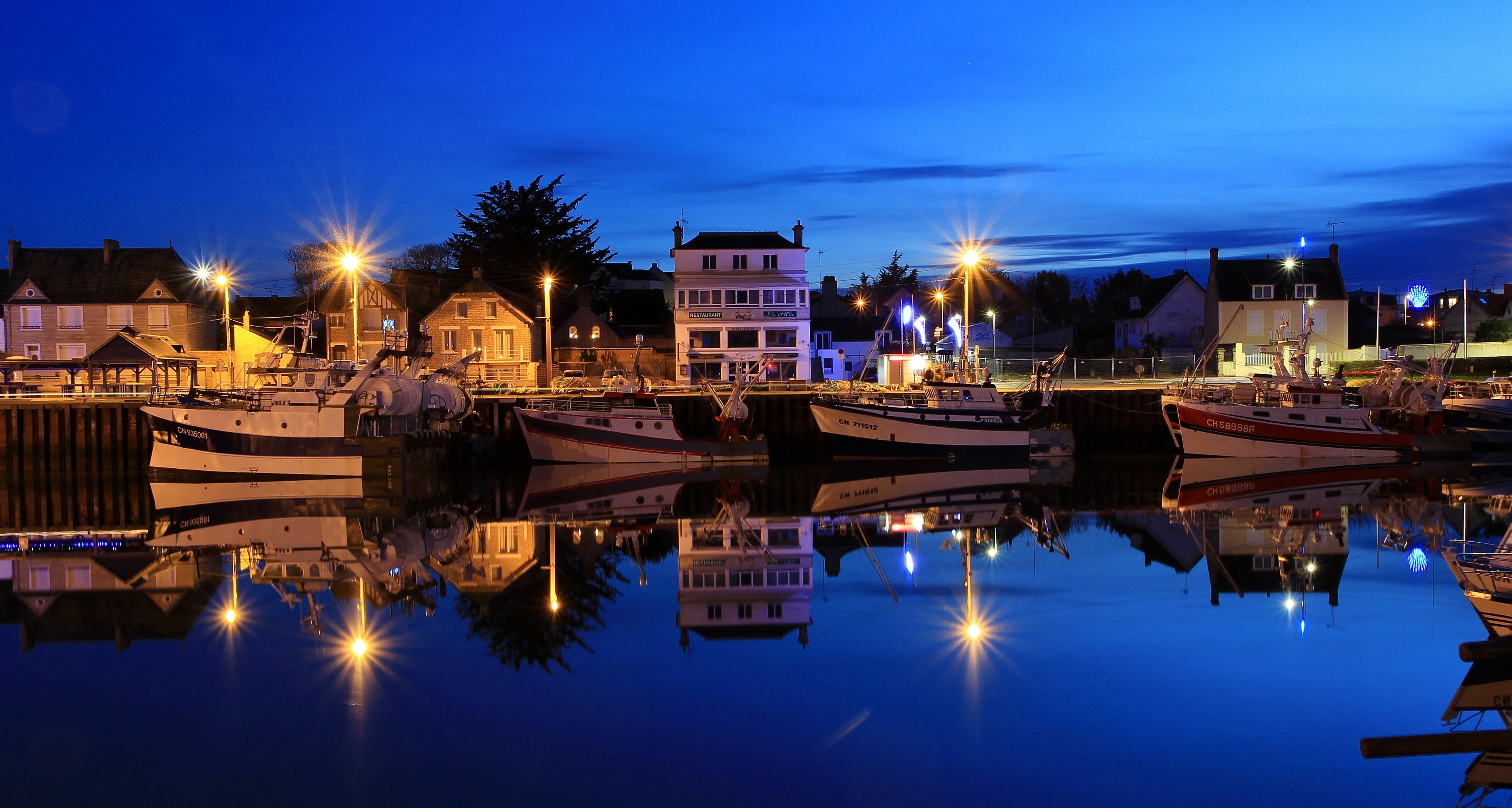 Boats docked in a harbor at night in Grandcamp-Maisy, France HD Wallpaper