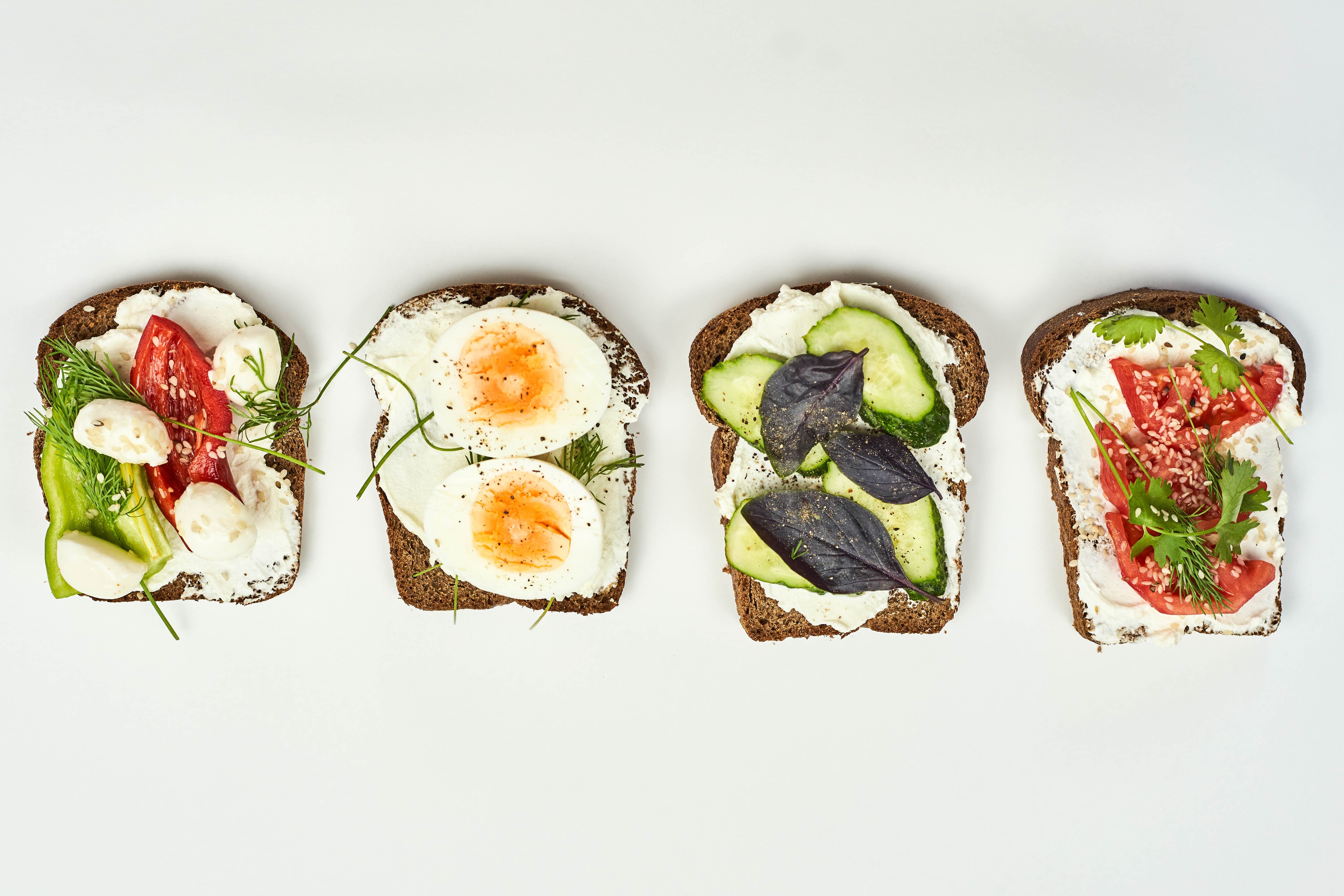 Four open-faced sandwiches with various toppings HD Wallpaper