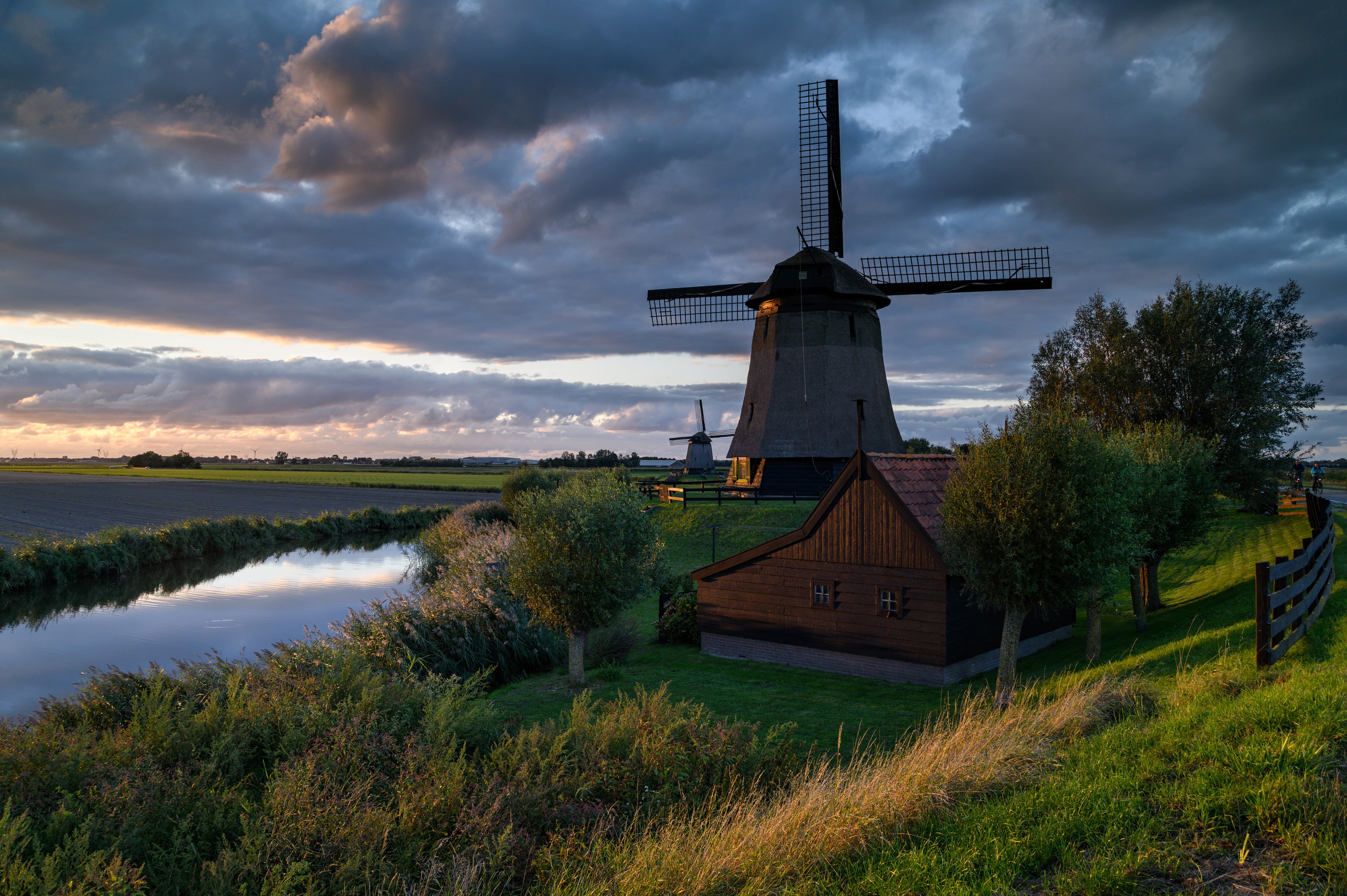 Windmills and a canal at sunset in Schermerhorn, Netherlands HD Wallpaper