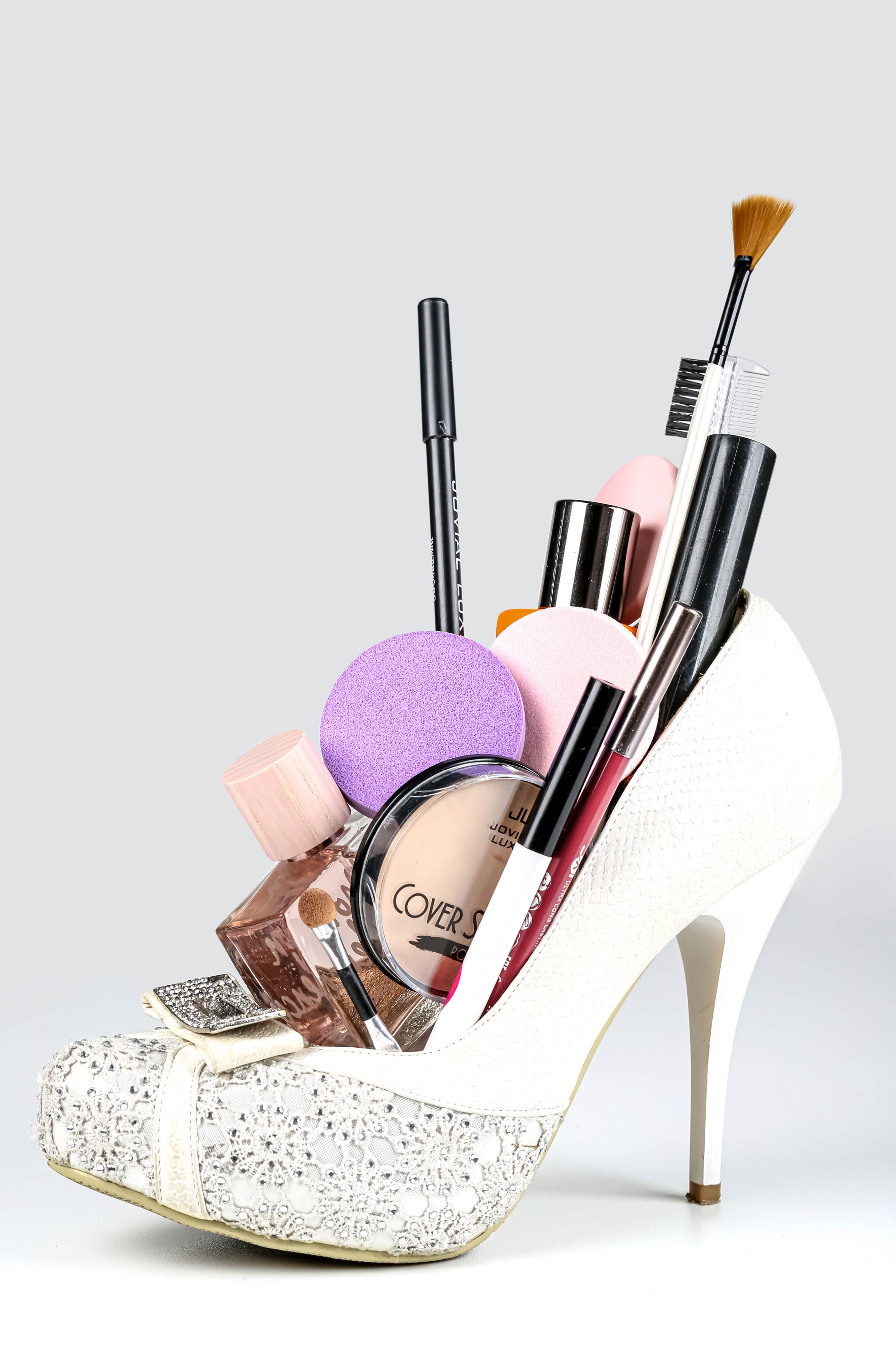 White stiletto heel filled with makeup and perfume HD Phone Wallpaper