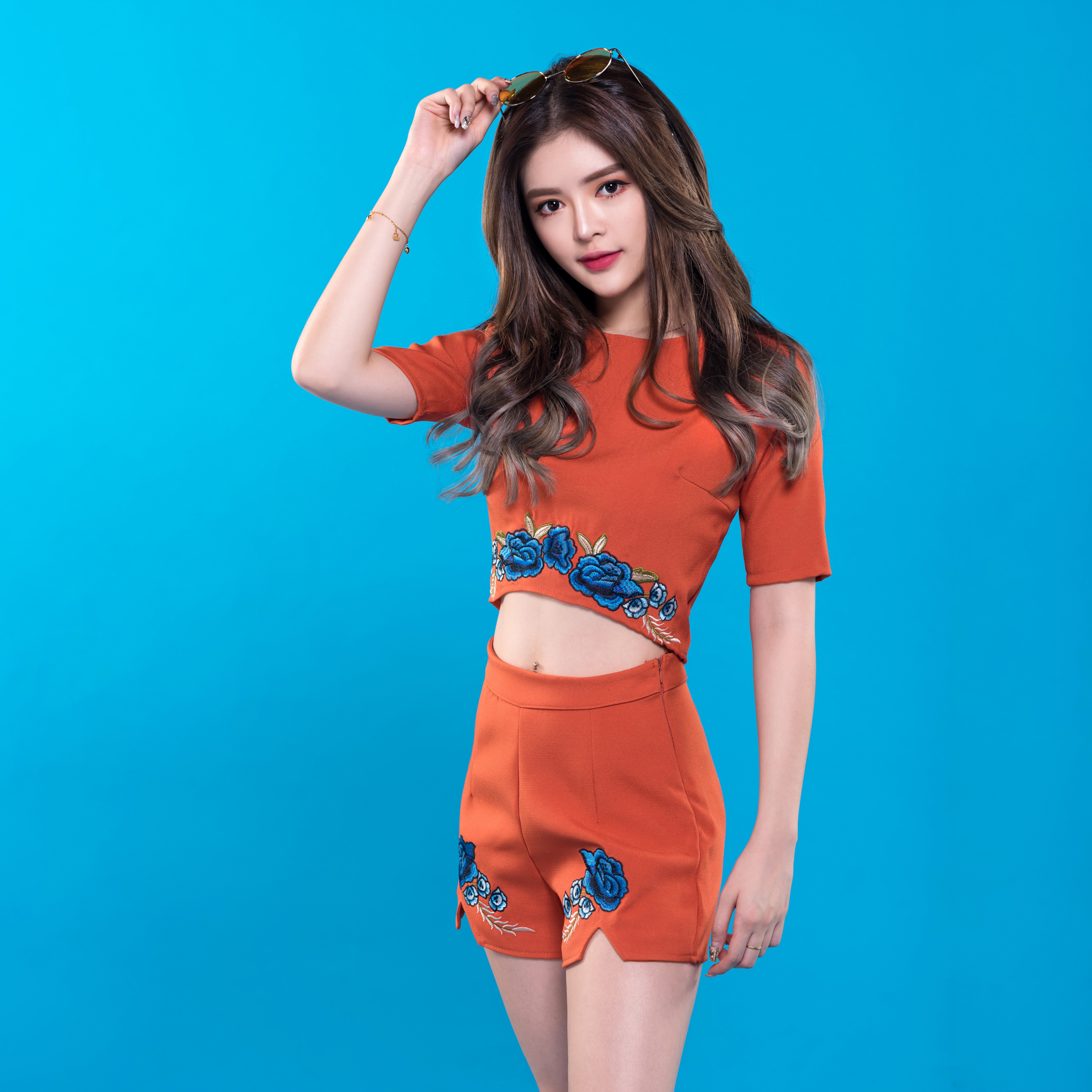 Asian woman in orange outfit with blue flowers HD Wallpaper
