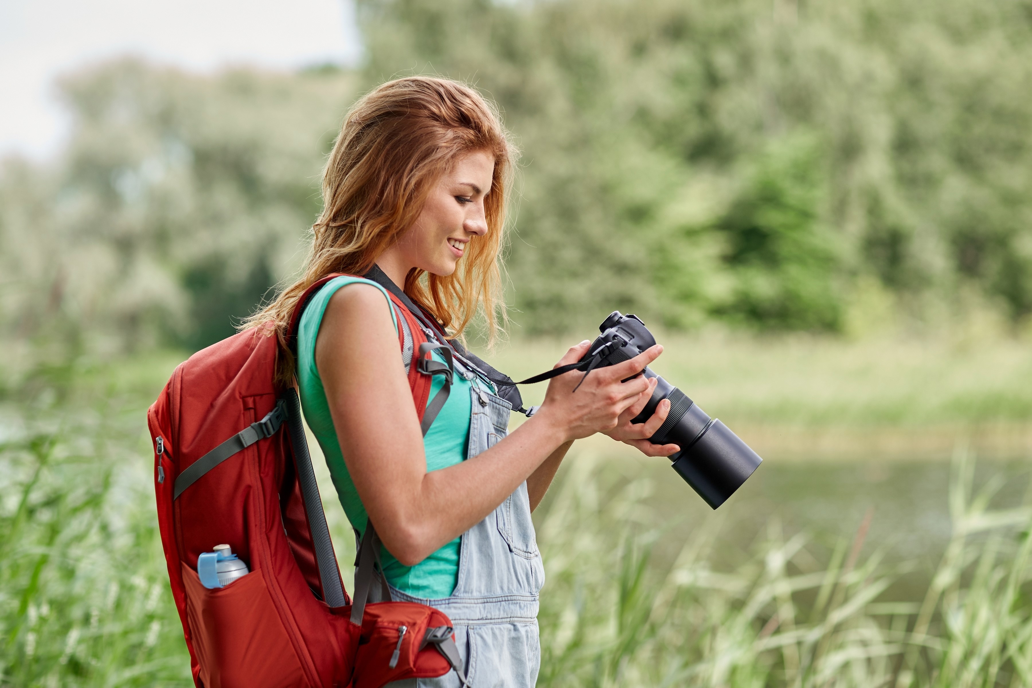 Woman with backpack and camera by a lake HD Wallpaper