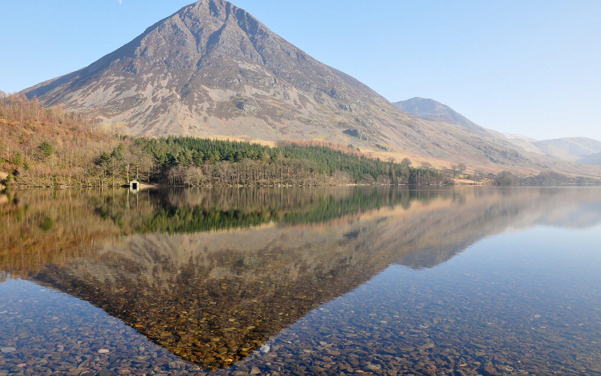 Mountain reflected in a clear lake with a boathouse HD Wallpaper