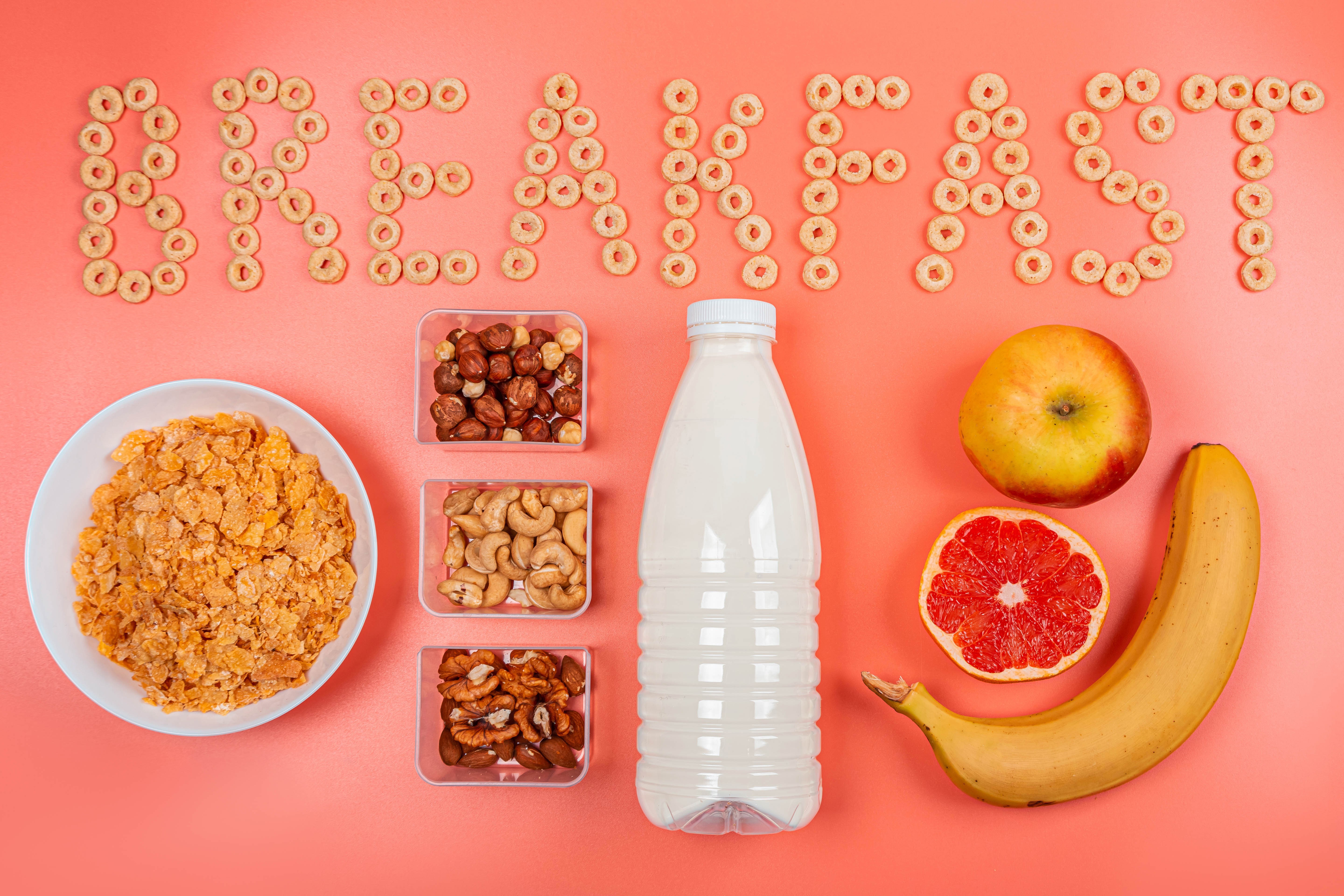 Breakfast cereal, nuts, milk, and fruit arranged on a pink background HD Wallpaper