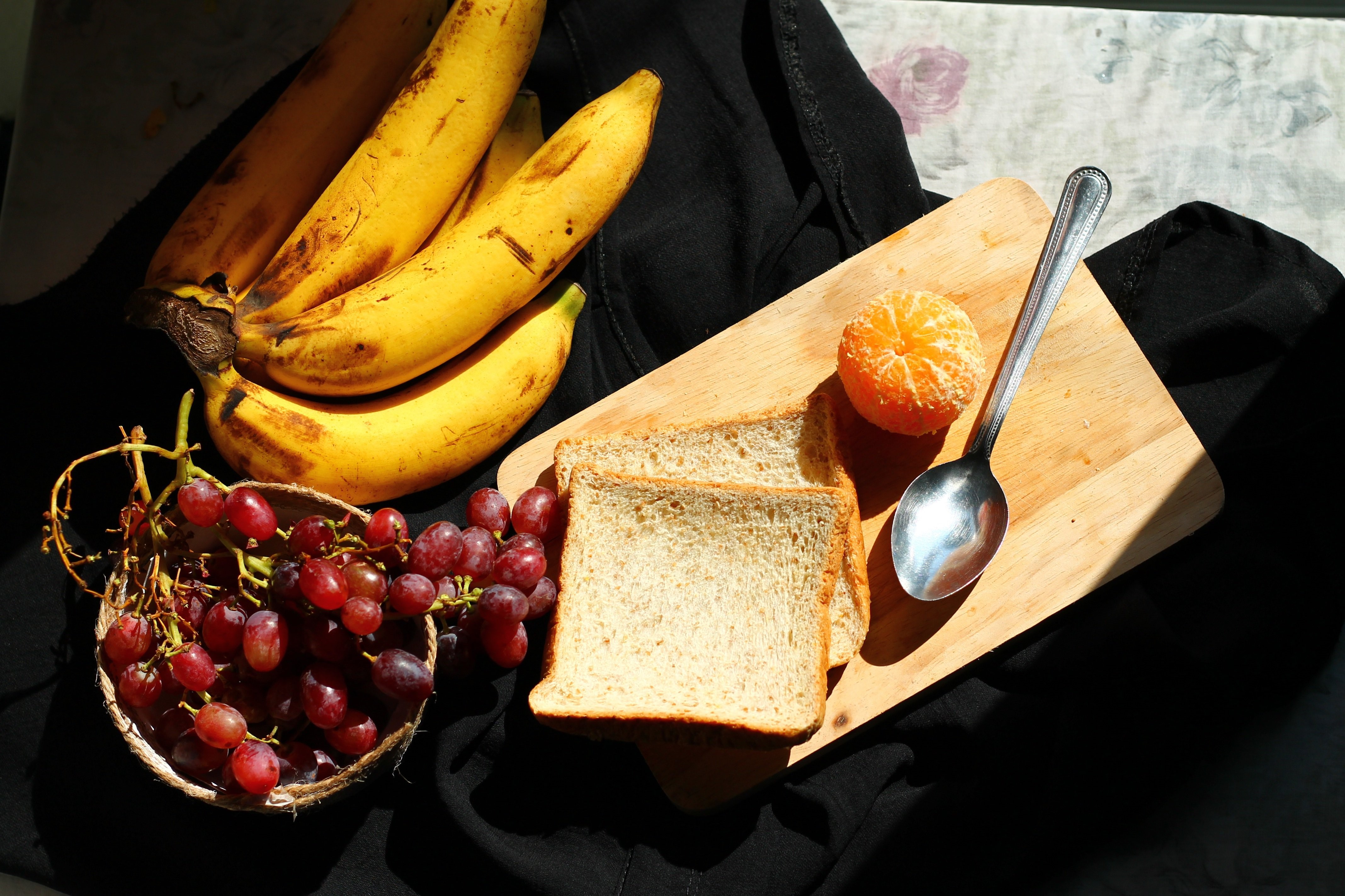 Bananas, Grapes, Bread, Mandarin, and Spoon on Cutting Board HD Wallpaper