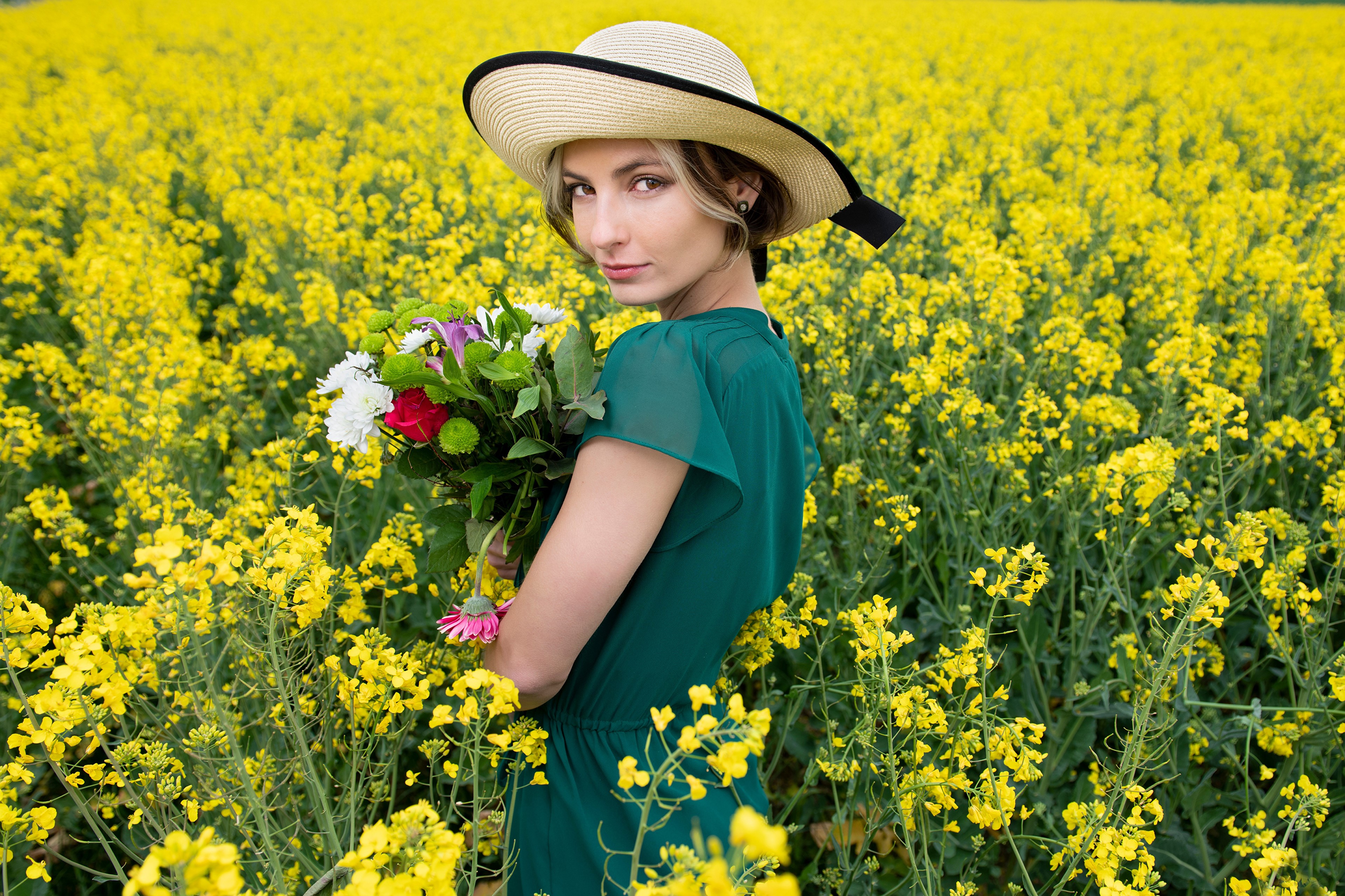 Woman in Hat Holding Flowers in Rapeseed Field HD Wallpaper