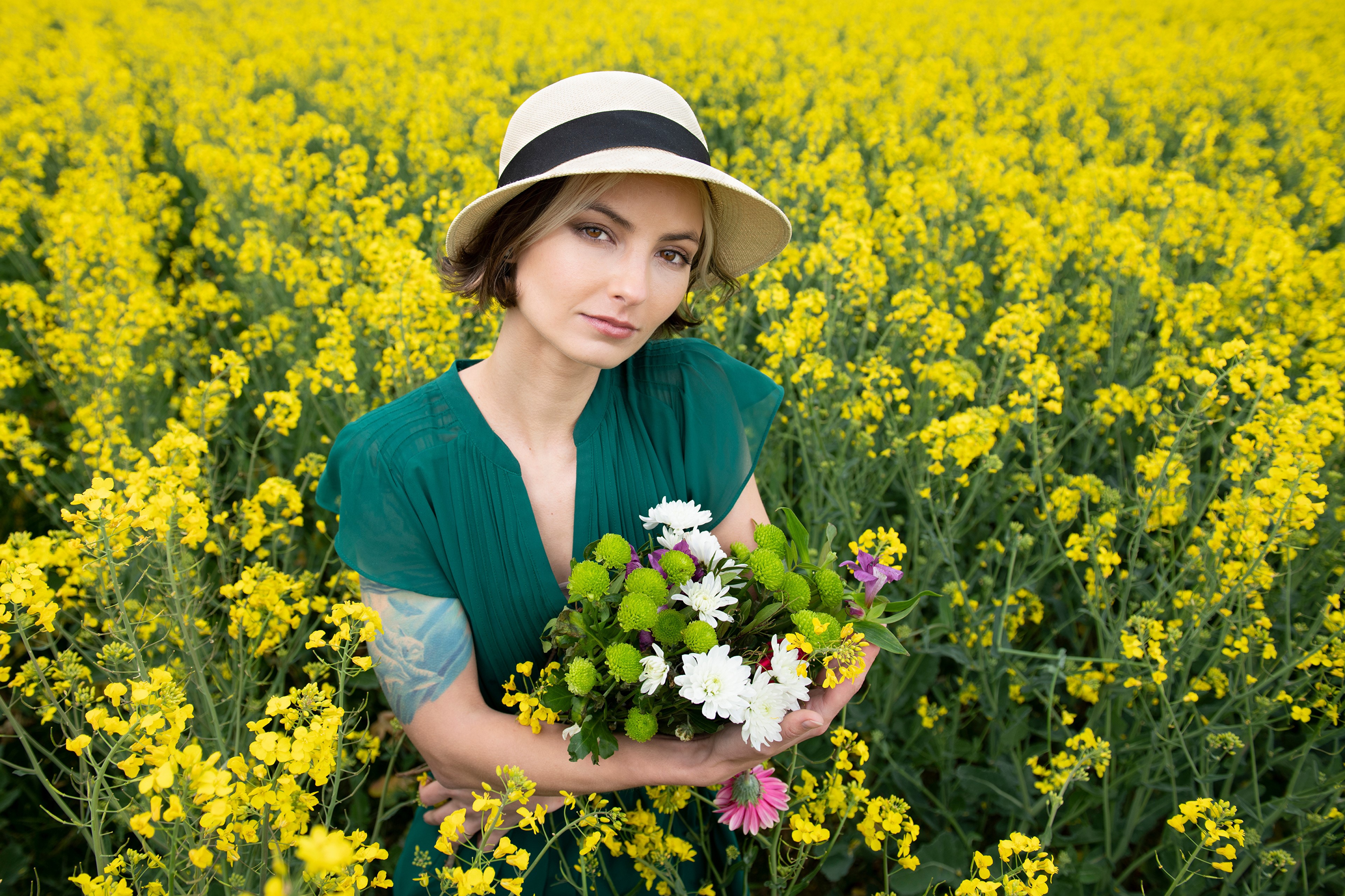 Woman in Hat Holding Flowers in Rapeseed Field HD Wallpaper