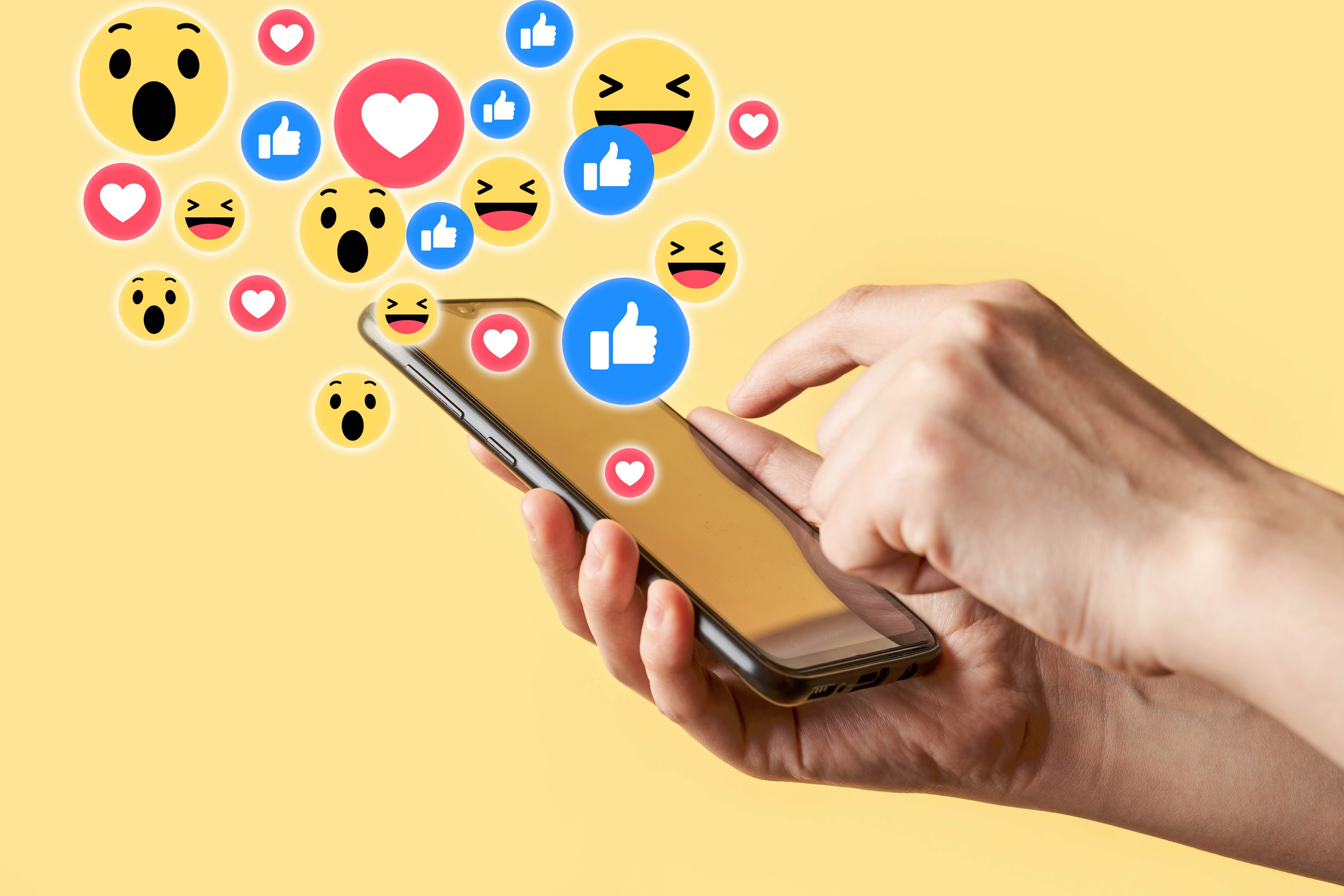 Smartphone with social media reactions on yellow background HD Wallpaper