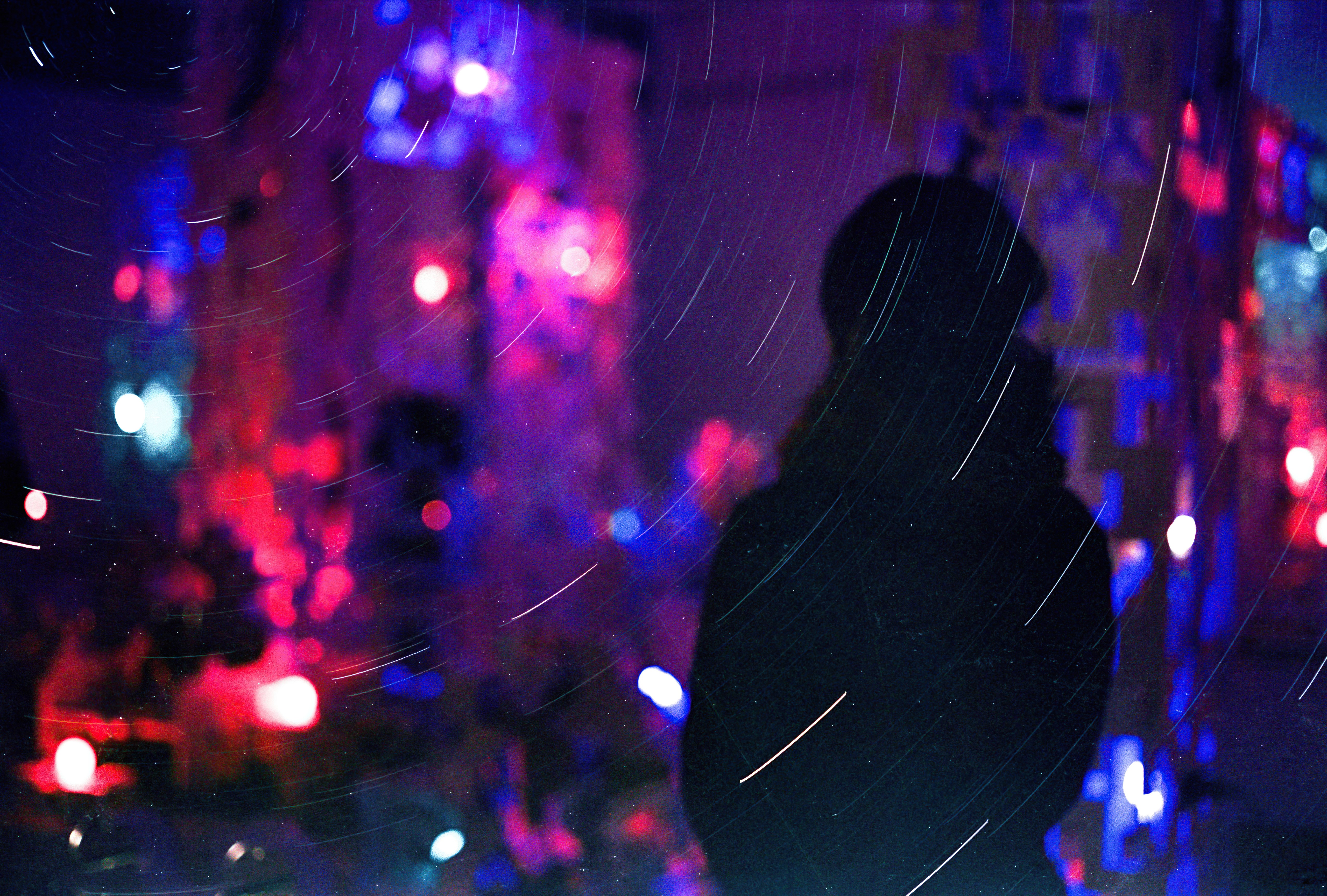 Silhouette of a person against colorful lights and star trails HD Wallpaper