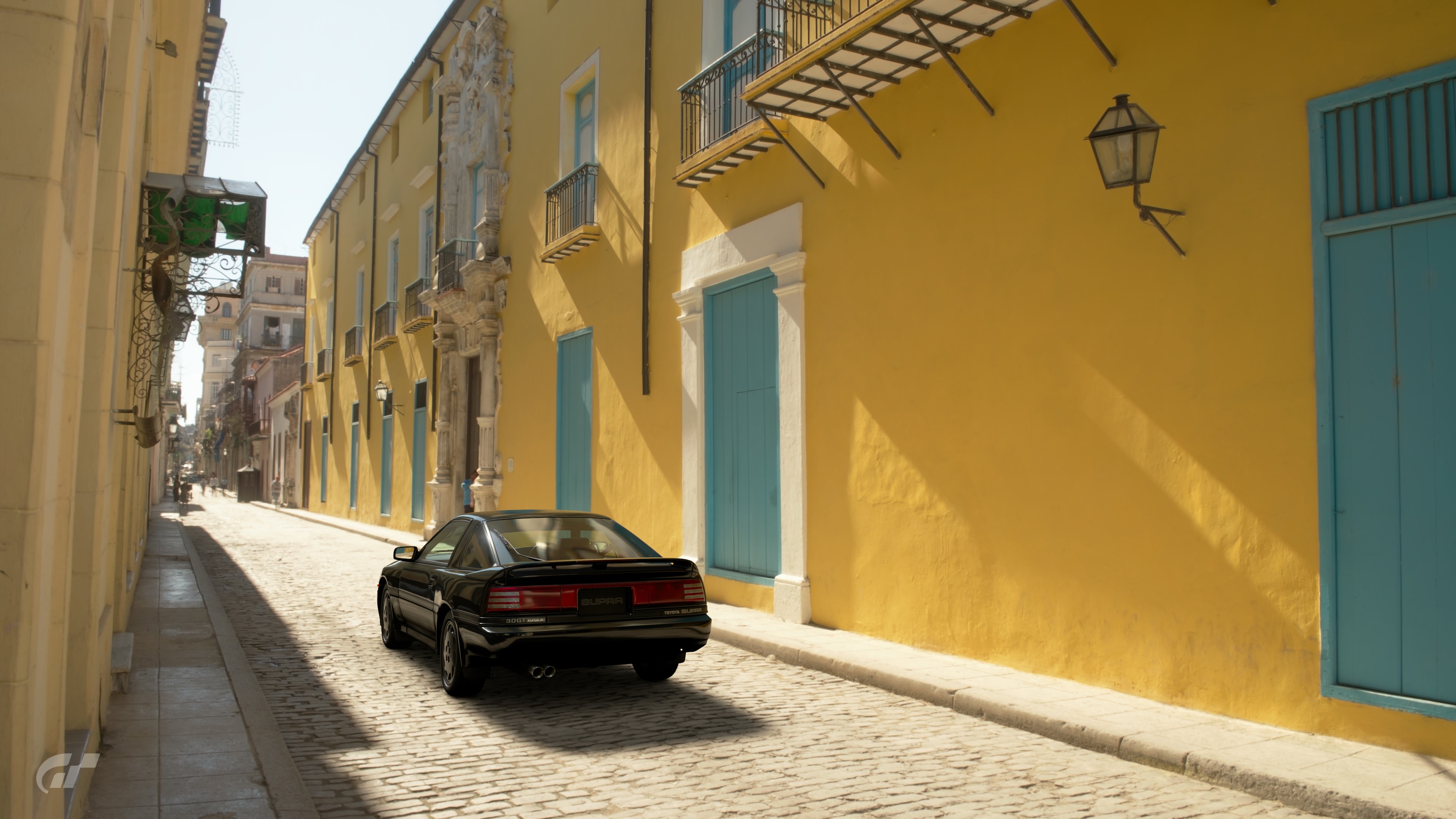 Black car on a cobblestone street in a city HD Wallpaper