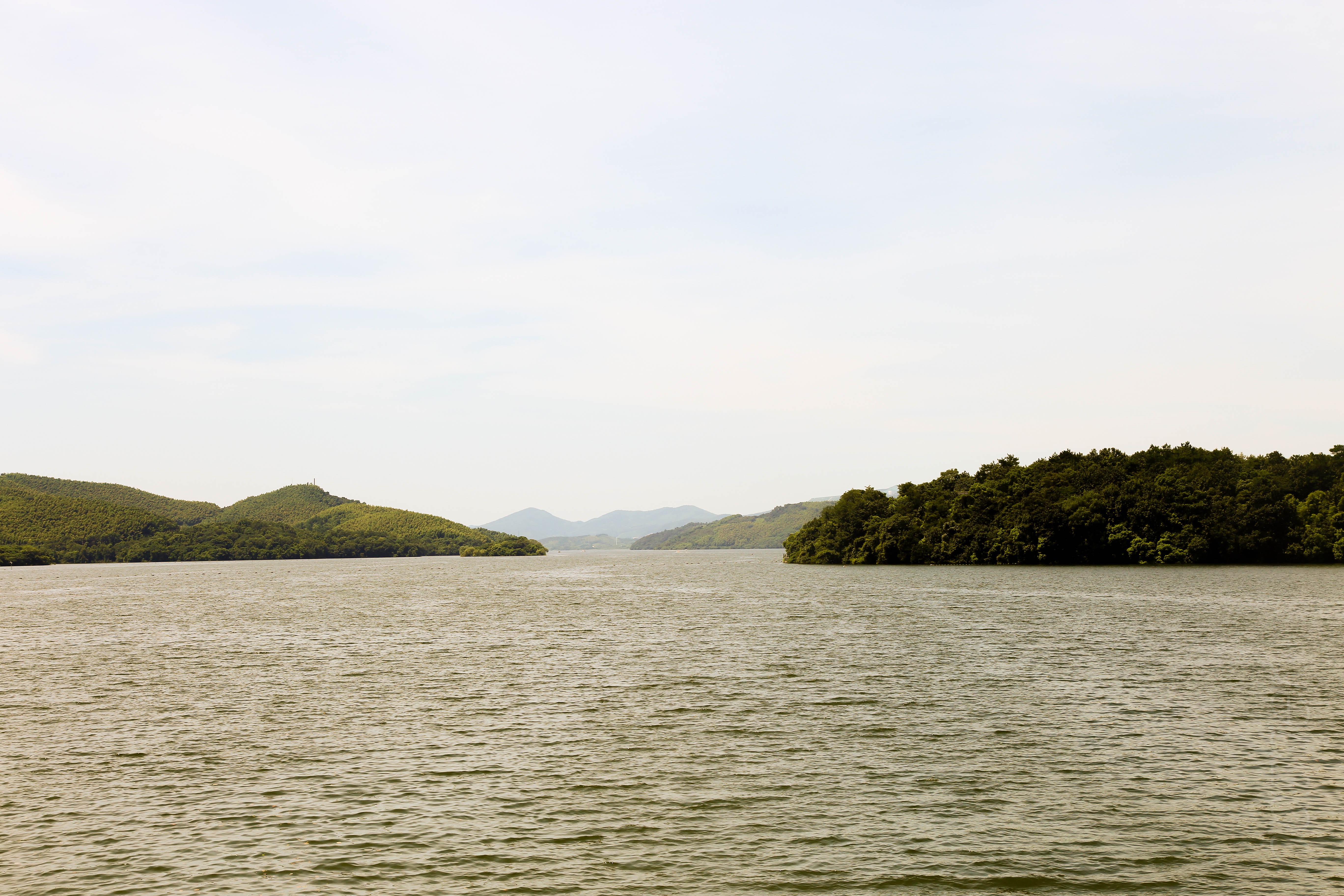 Green islands in a lake under a cloudy sky HD Wallpaper