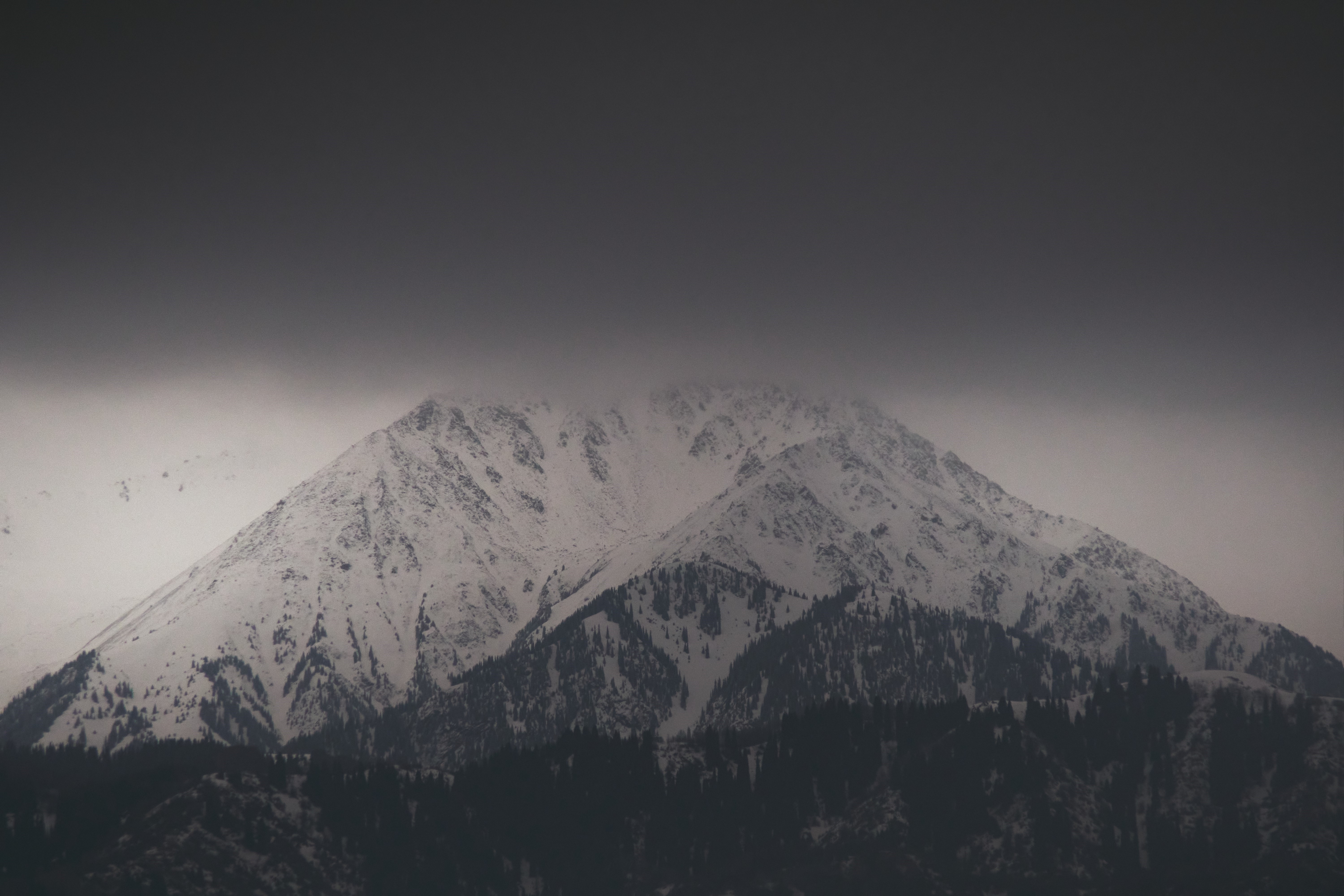 Snowy mountains under dark clouds HD Wallpaper