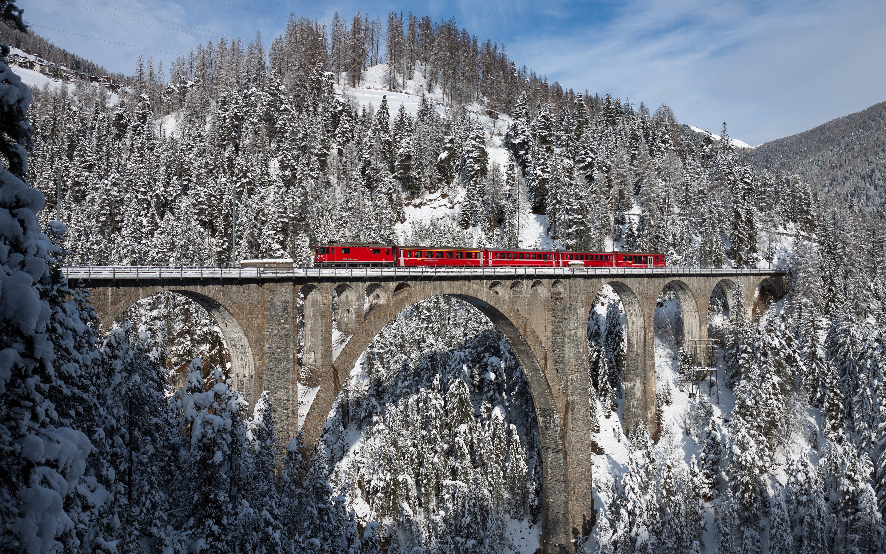 Bernina Express train crossing a snowy viaduct in the Swiss Alps HD Wallpaper