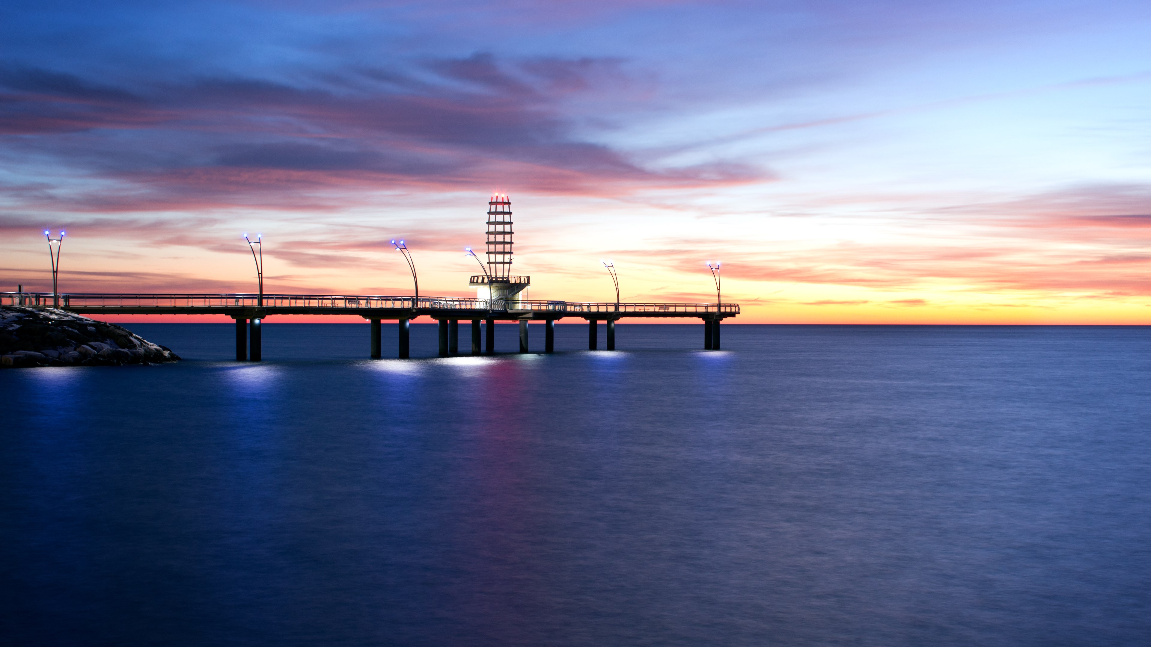 Pier with tower and lights over water at sunset HD Wallpaper