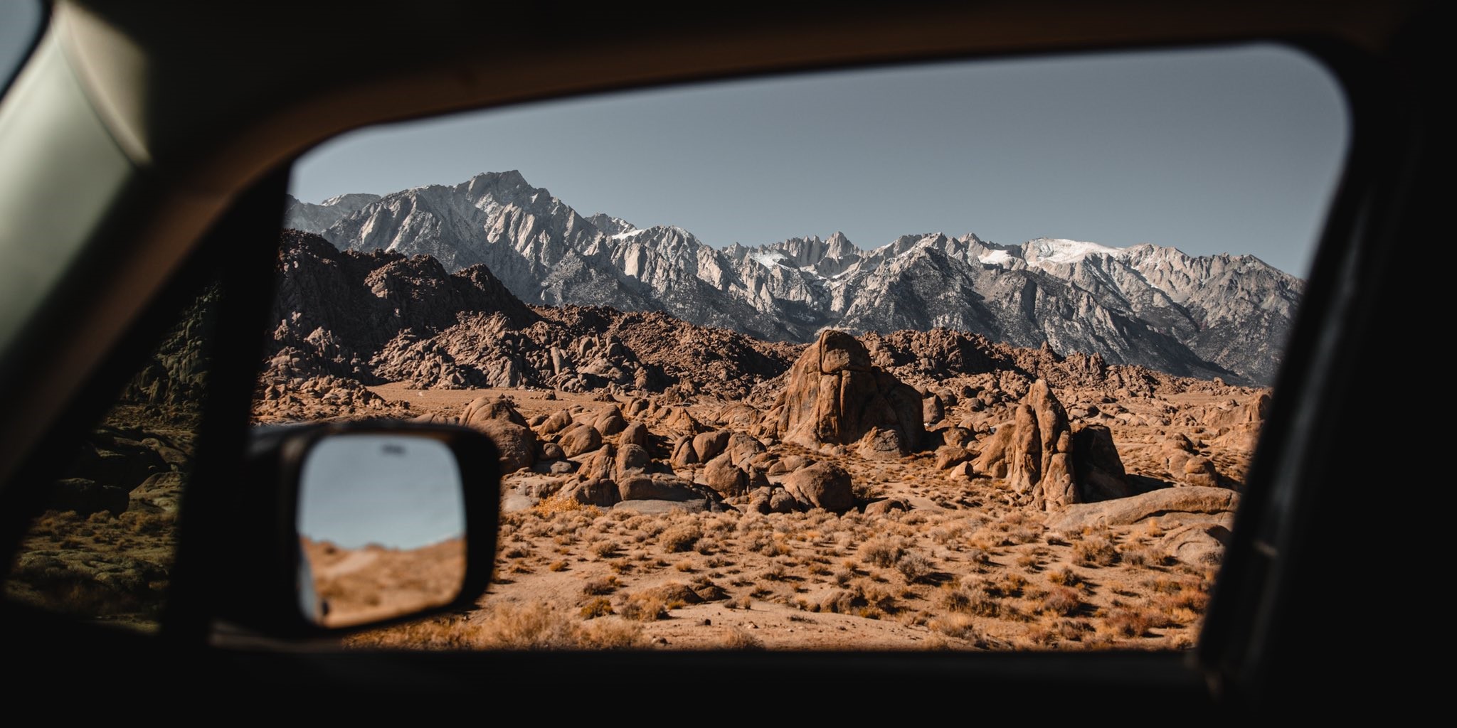View of snow-capped mountains through a car window HD Wallpaper
