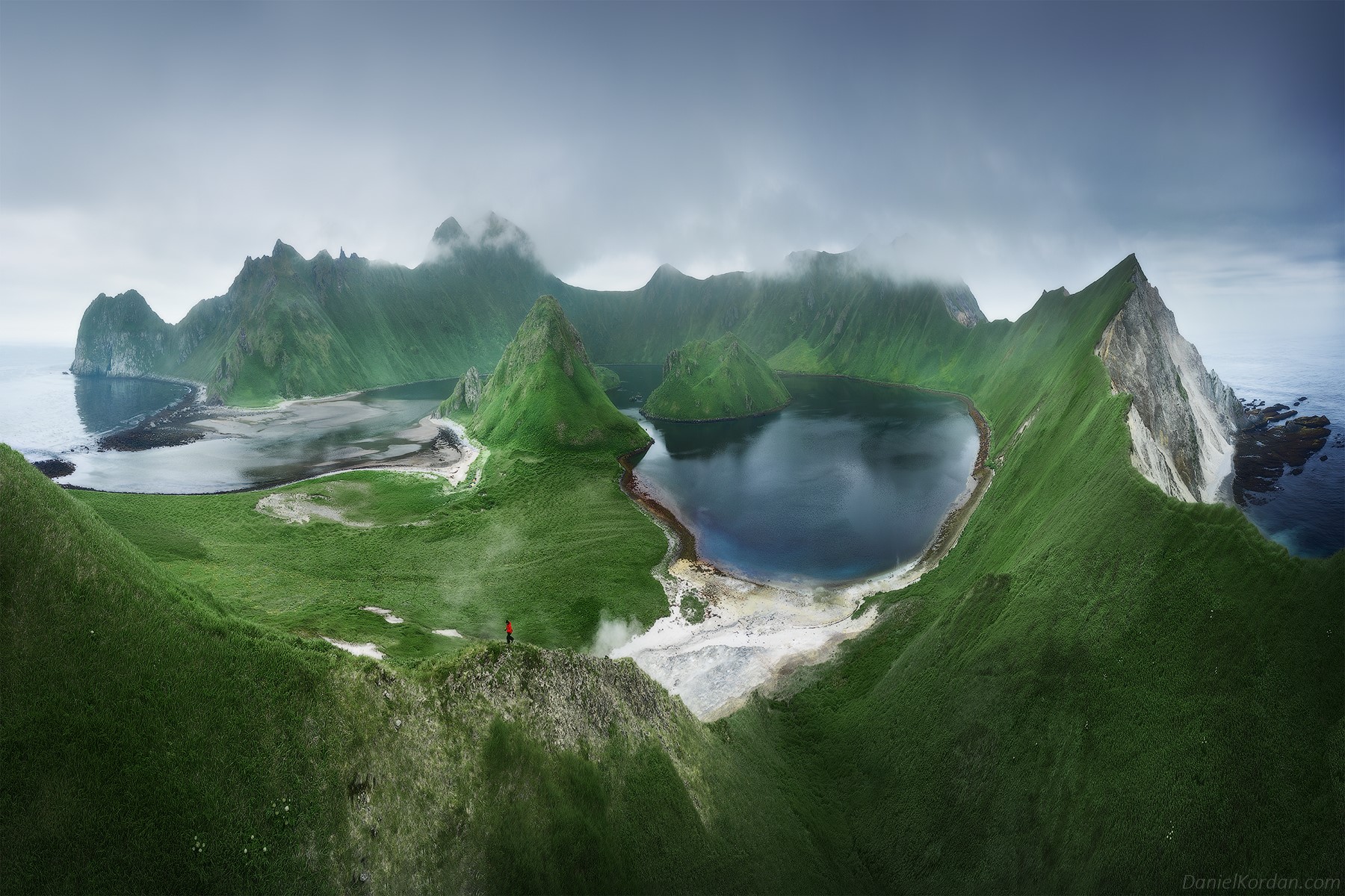 Panoramic view of a green, mountainous island with a lake and ocean HD Wallpaper