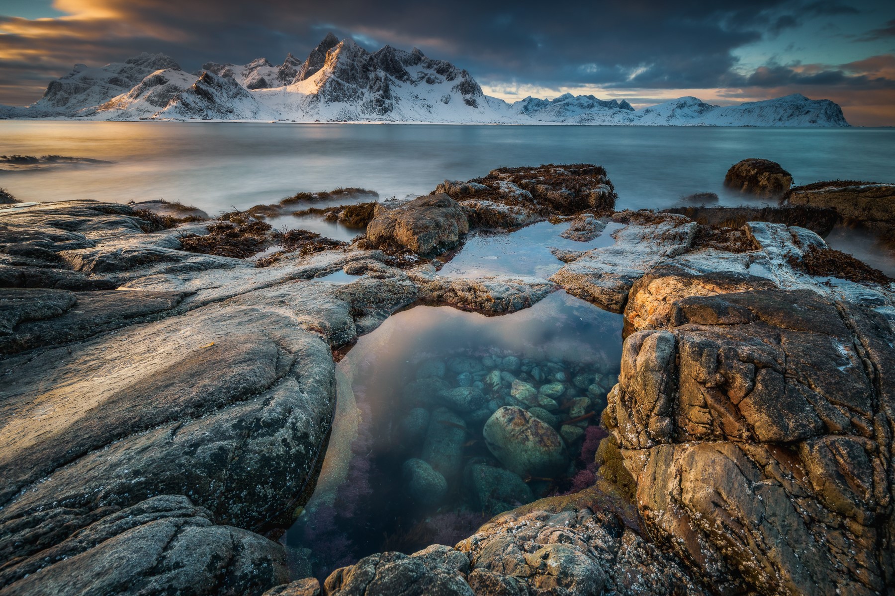 Snow-capped mountains and rocky shore at sunset HD Wallpaper