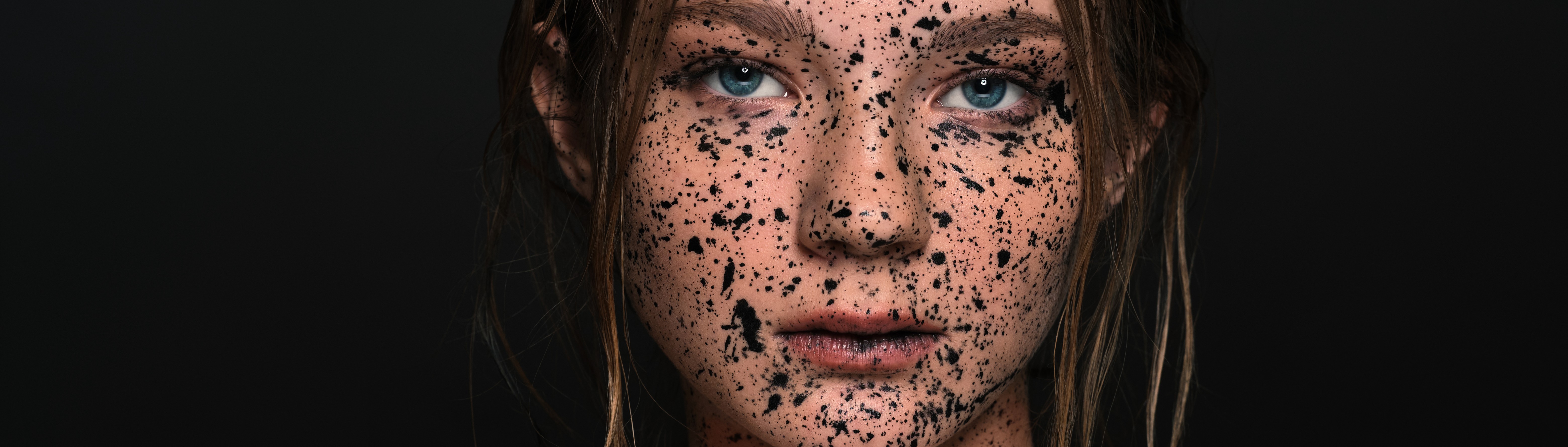 Woman with black paint splatters on face HD Wallpaper