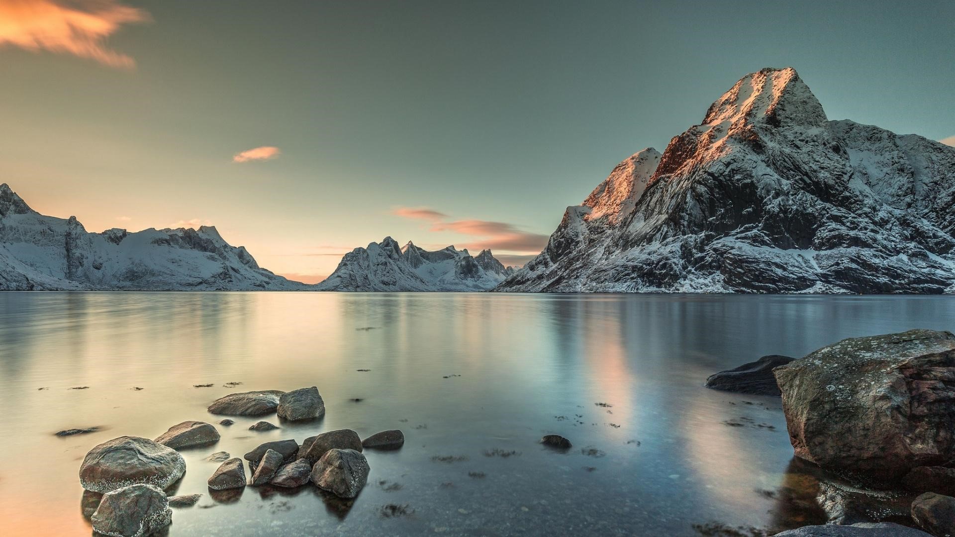 Snow-capped mountains reflected in a calm lake at sunset HD Wallpaper