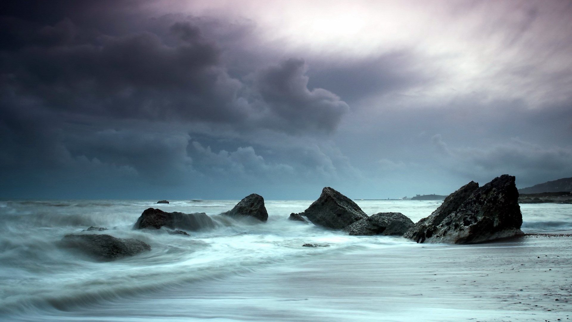 Stormy ocean waves crash against rocks on a beach HD Wallpaper