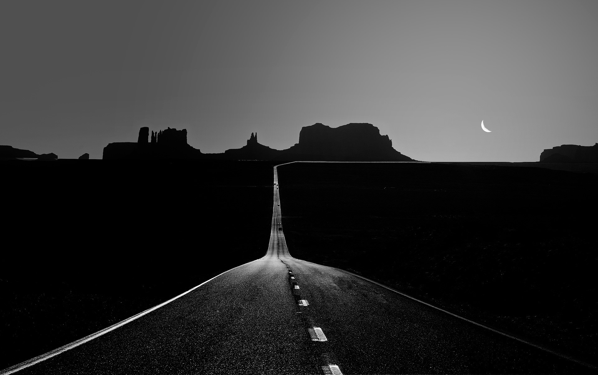 Monochrome road leading to Monument Valley with crescent moon HD Wallpaper