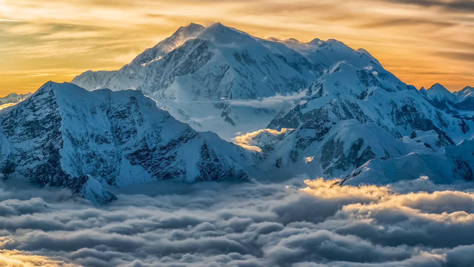 Snow-covered mountains above clouds at sunset HD Wallpaper