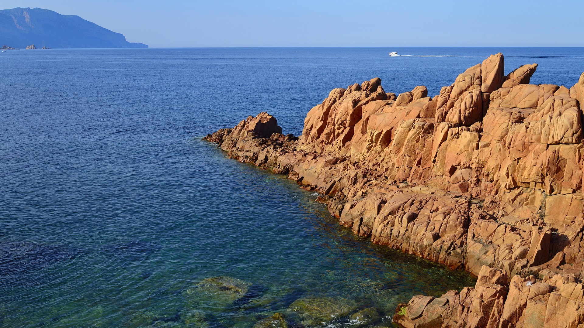 Red rocks and blue sea with a distant boat HD Wallpaper