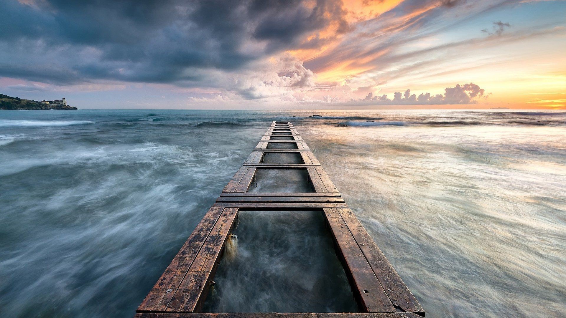 Wooden pier extending into the sea at sunset HD Wallpaper