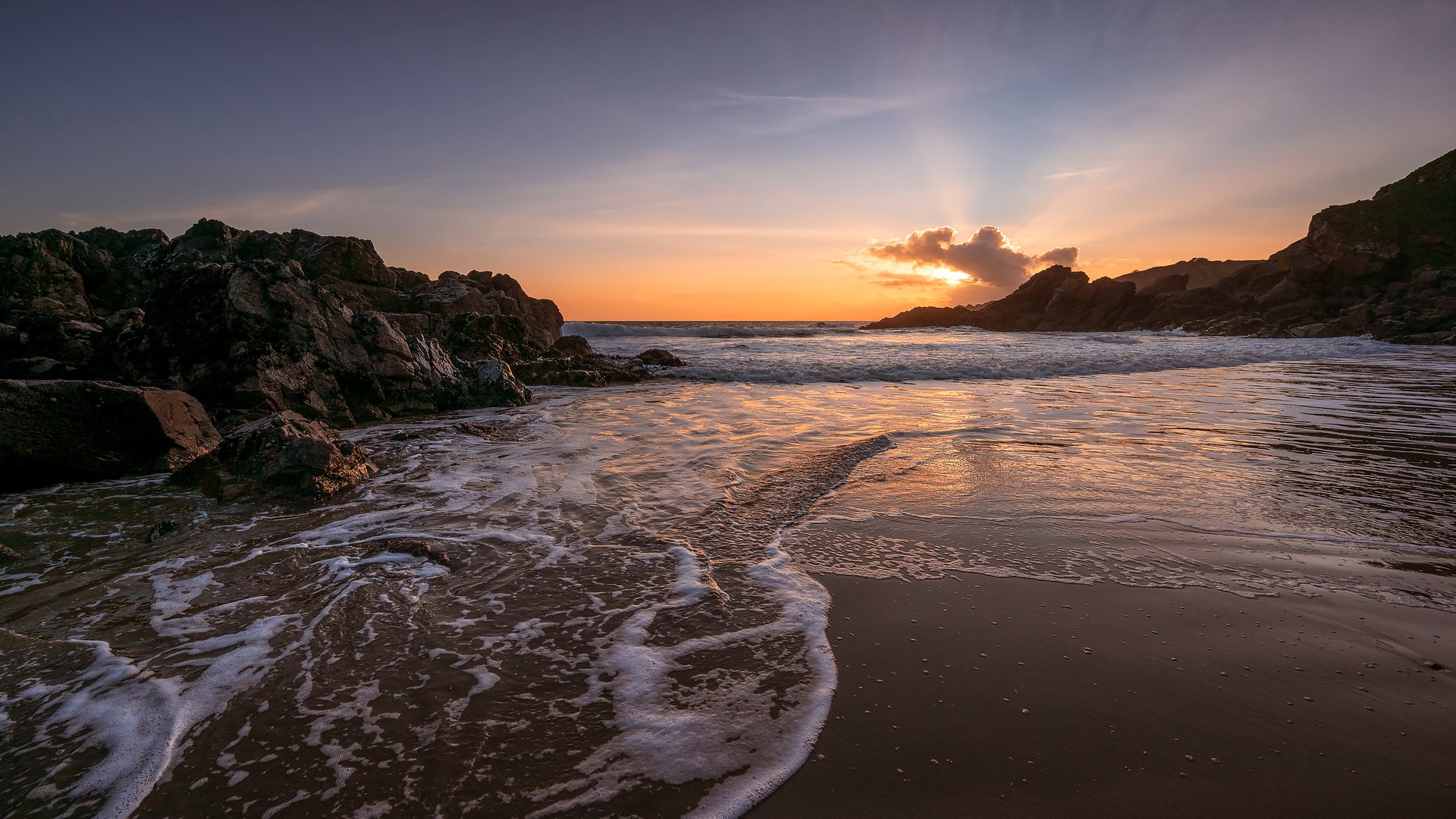 Sunset over a rocky beach with waves HD Wallpaper