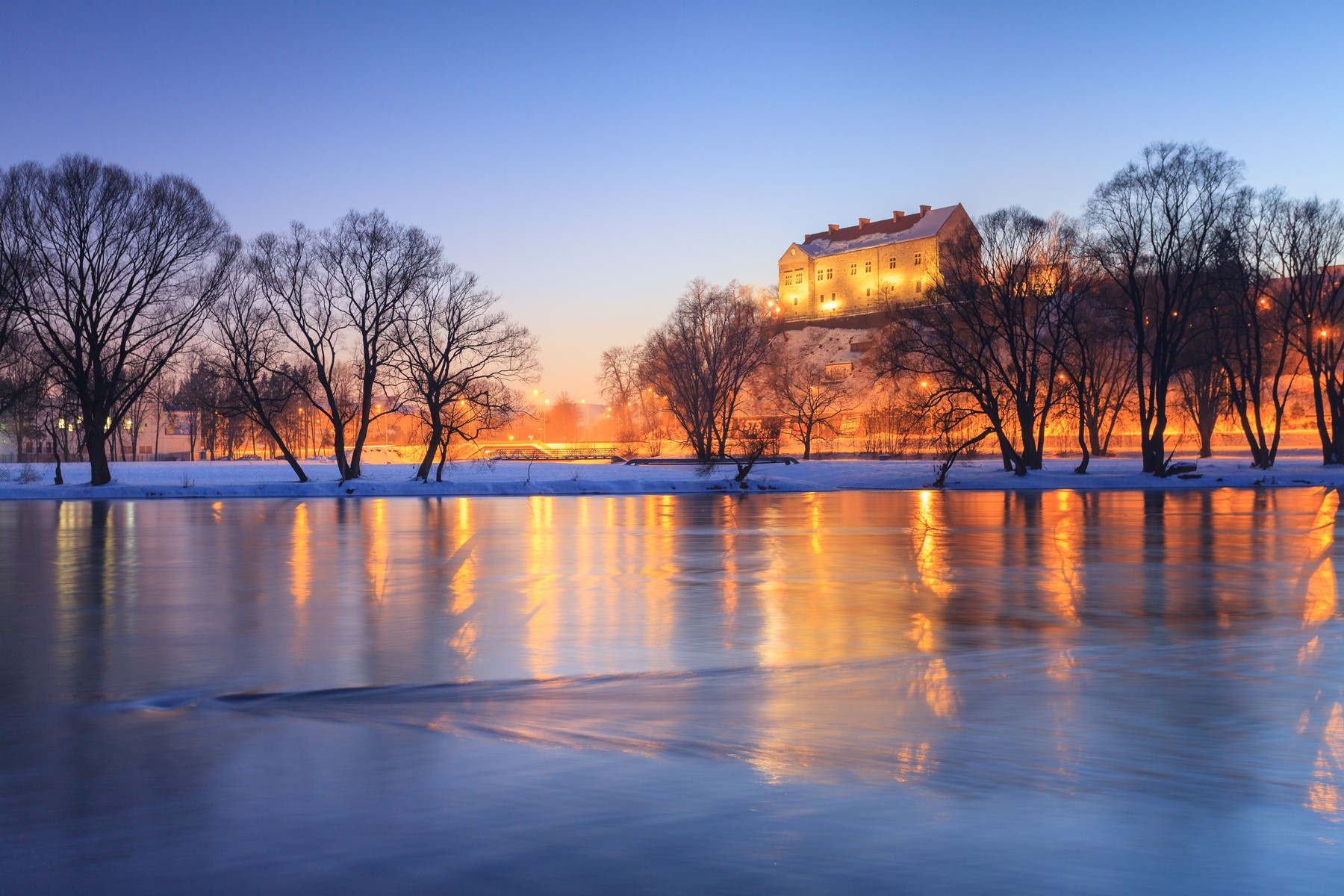 Winter castle on a hill reflected in a river at night HD Wallpaper