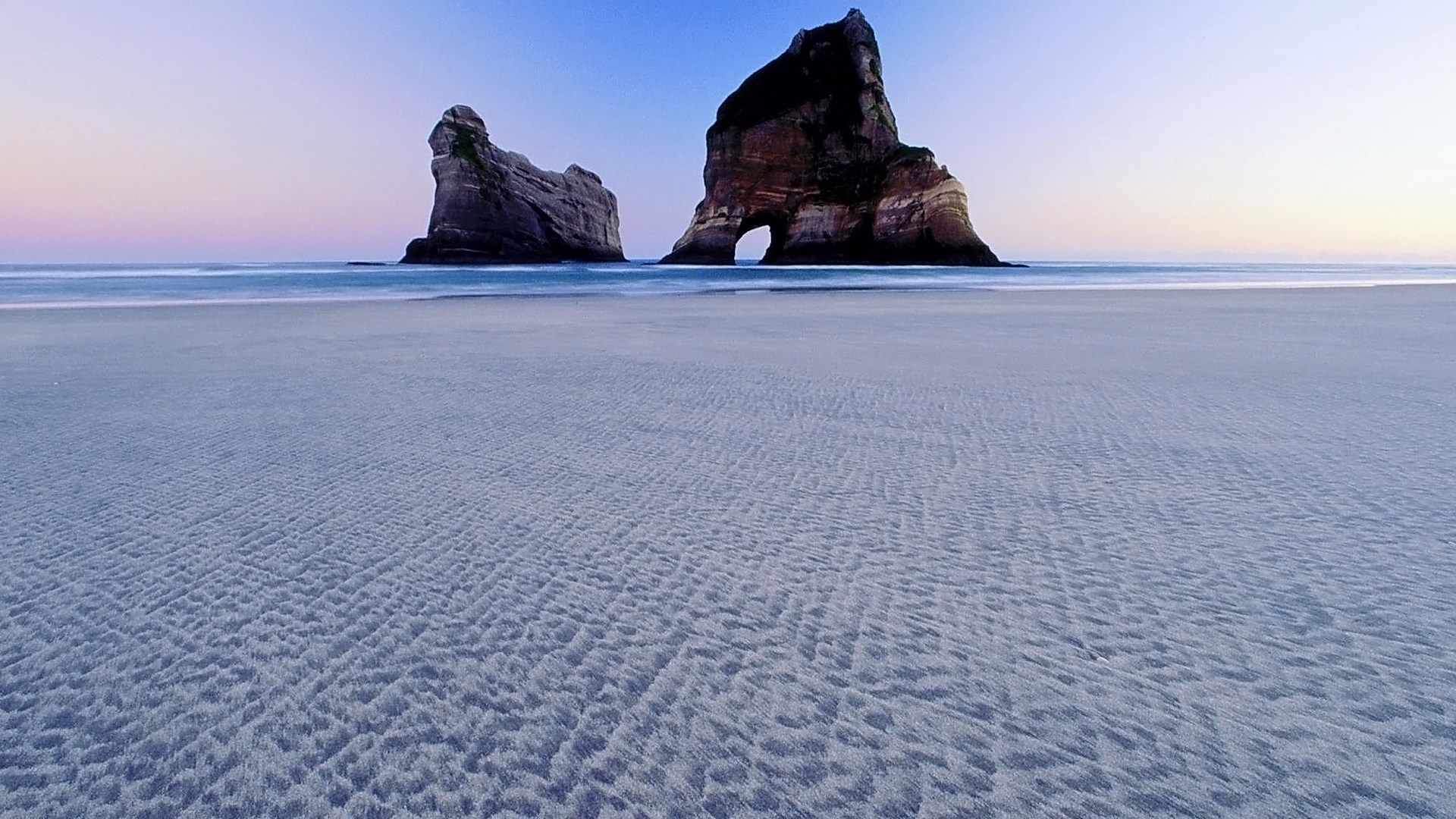 Rock formations on a beach at sunset HD Wallpaper