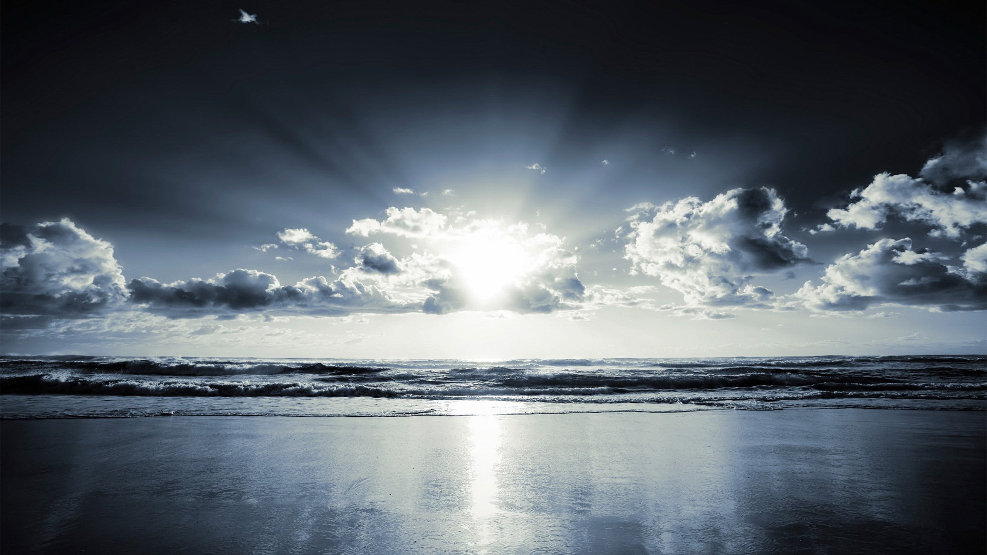 Sunbeams breaking through clouds over a beach and ocean HD Wallpaper