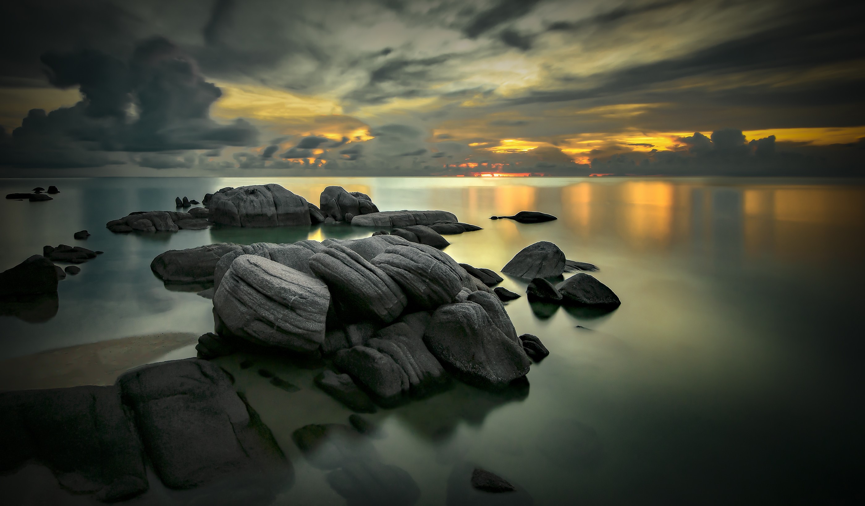 Rocky shore at dusk with dramatic clouds and ocean reflection HD Wallpaper