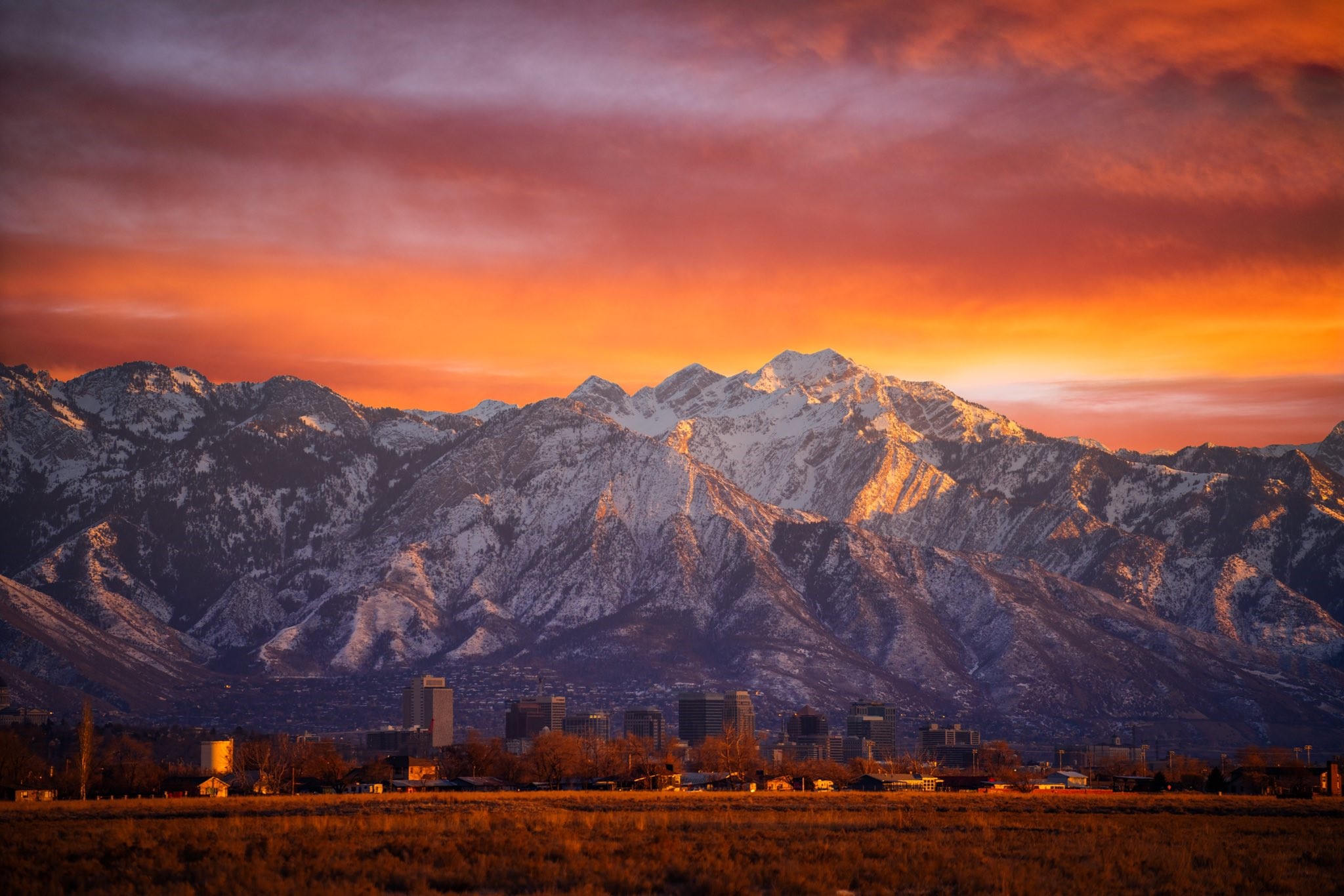 Sunset over snowy mountains and city skyline HD Wallpaper