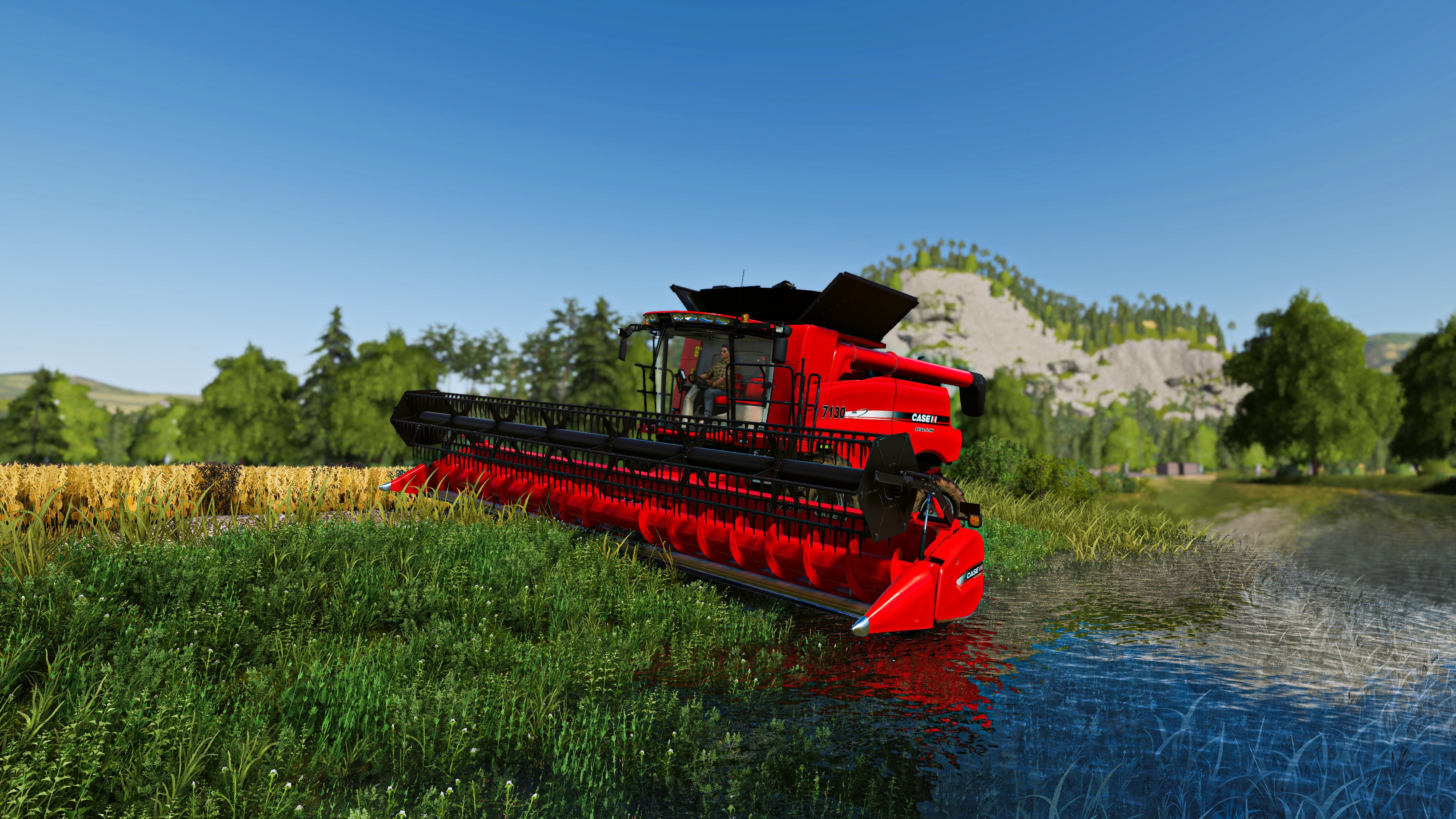 Red combine harvester in a field and water HD Wallpaper