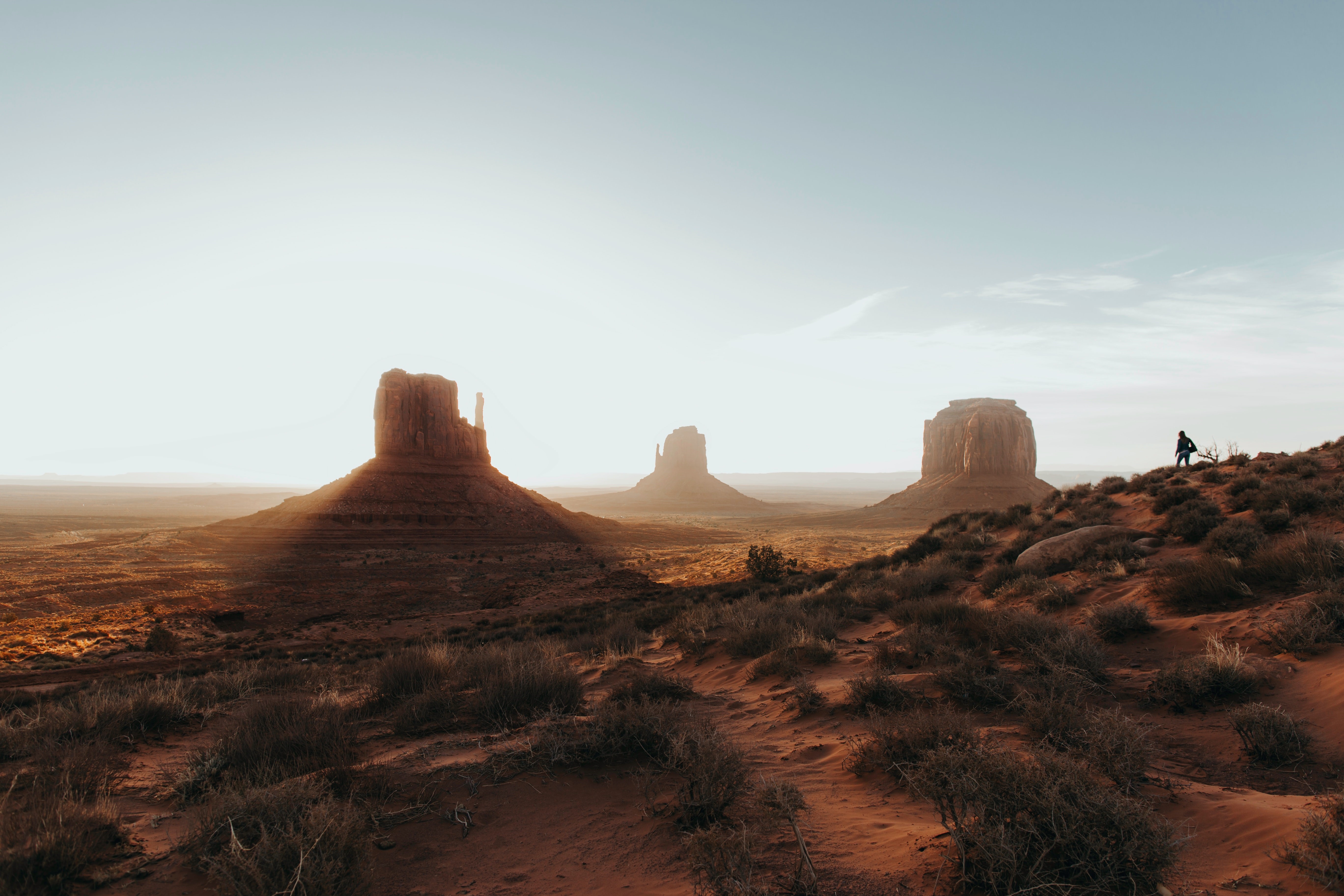Monument Valley landscape with rock formations and a person HD Wallpaper