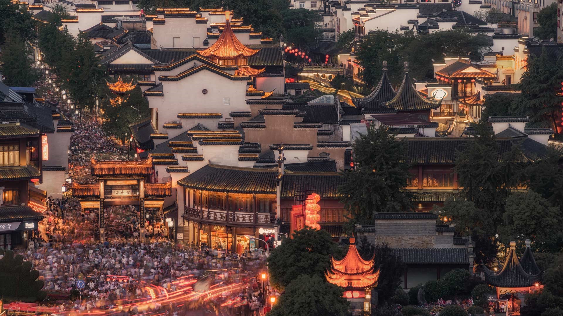 Night view of a bustling traditional Chinese town with illuminated buildings and crowds HD Wallpaper