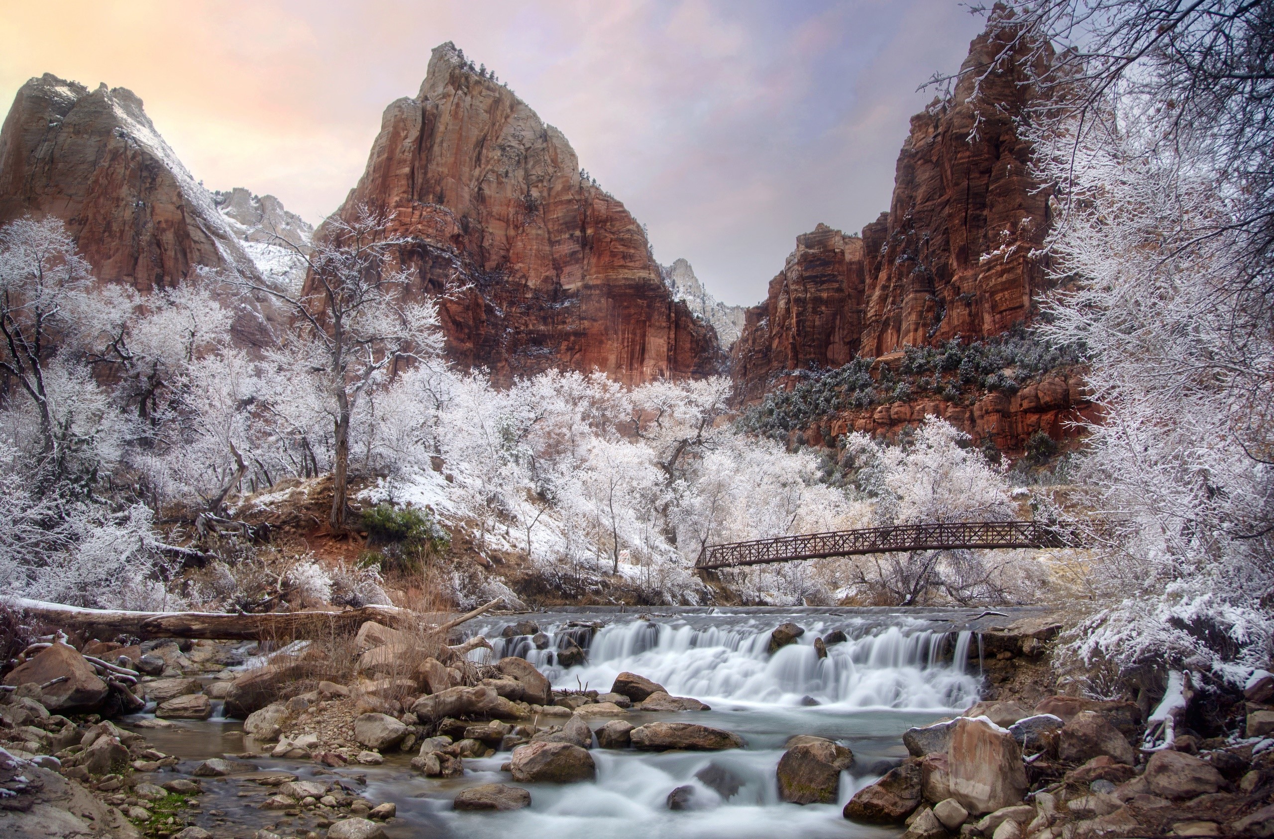 Winter scene with snow-covered trees, a bridge, and a waterfall in a rocky canyon HD Wallpaper