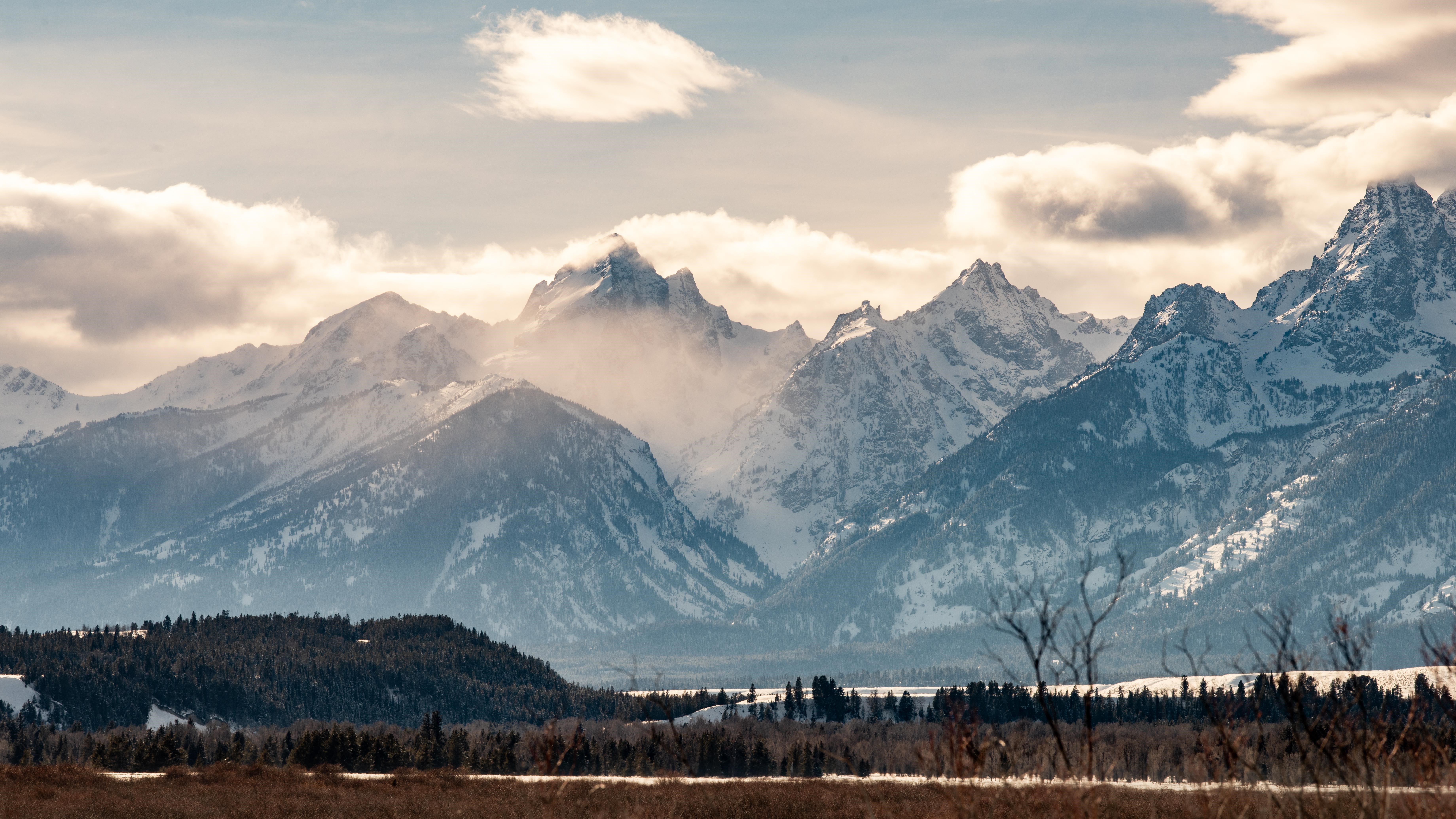 Snow-capped mountains under a cloudy sky HD Wallpaper