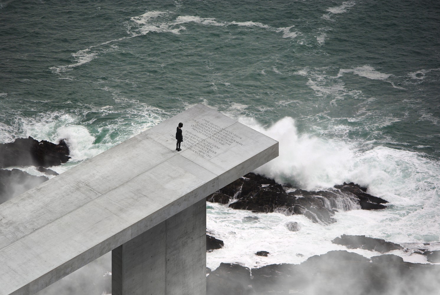 Modern concrete structure overlooking stormy ocean waves HD Wallpaper