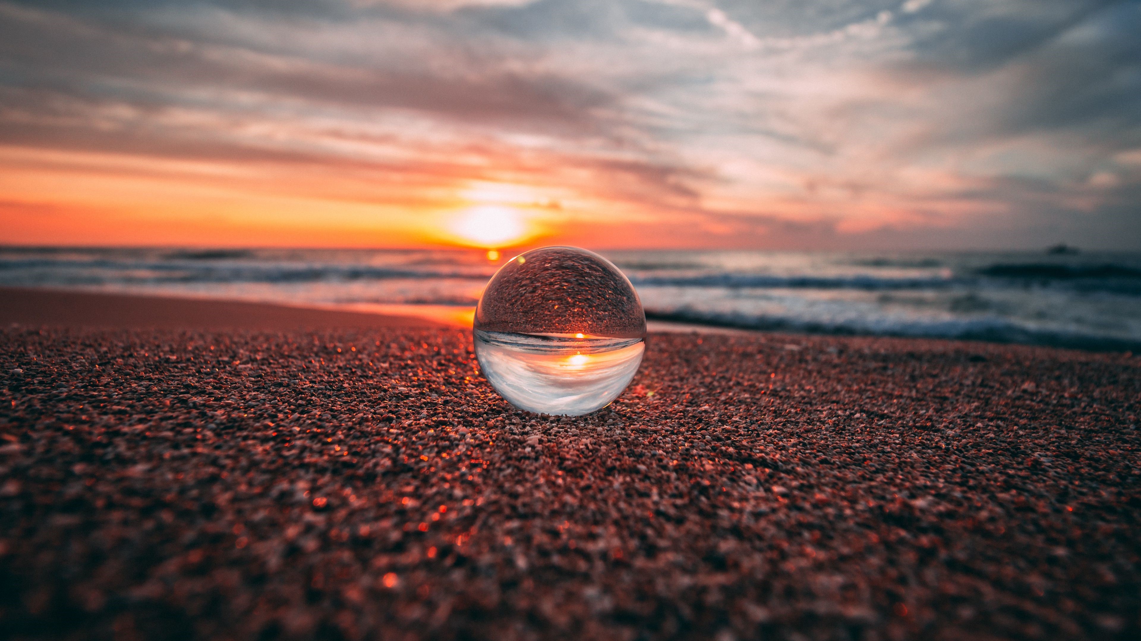 Sunset reflection in glass ball on beach HD Wallpaper