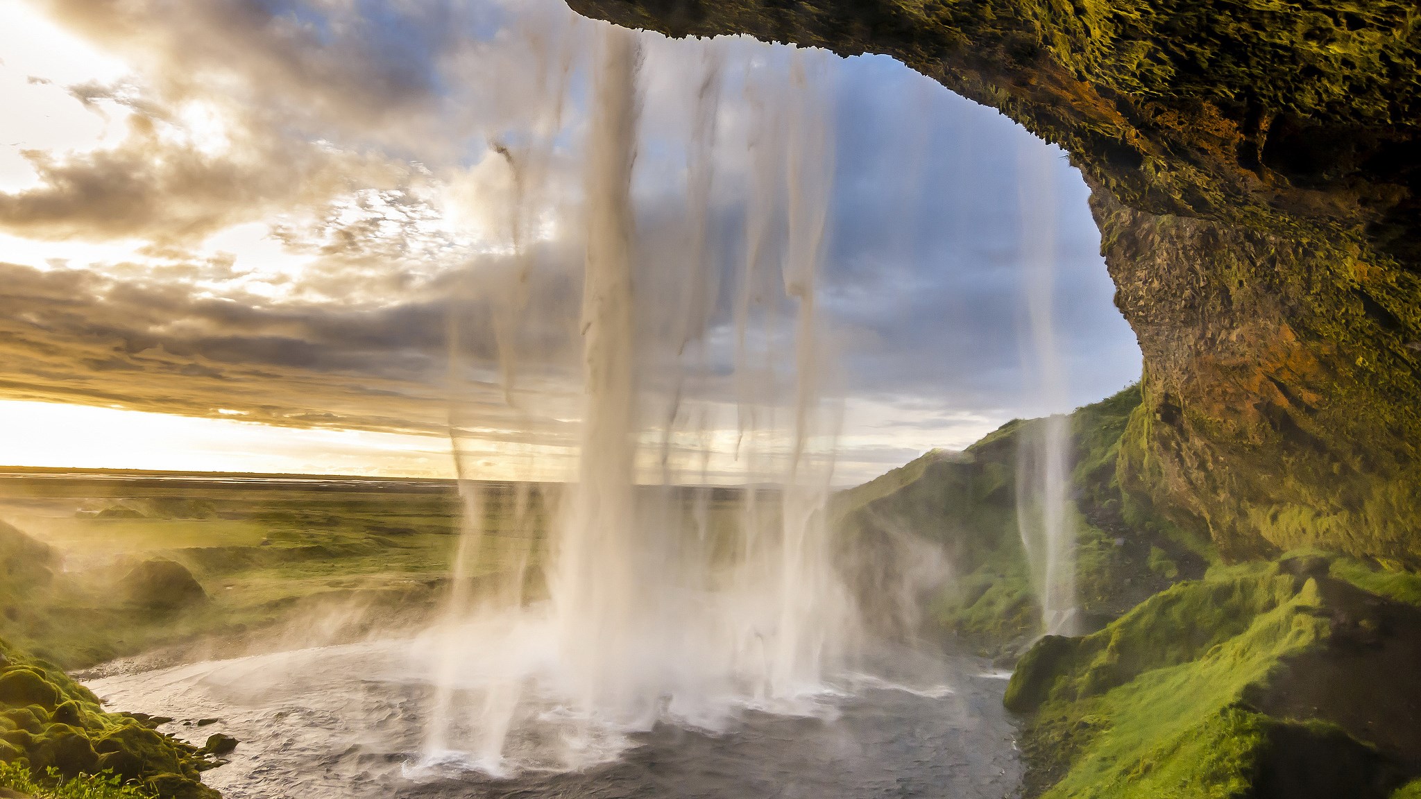 View from behind a waterfall at sunset HD Wallpaper