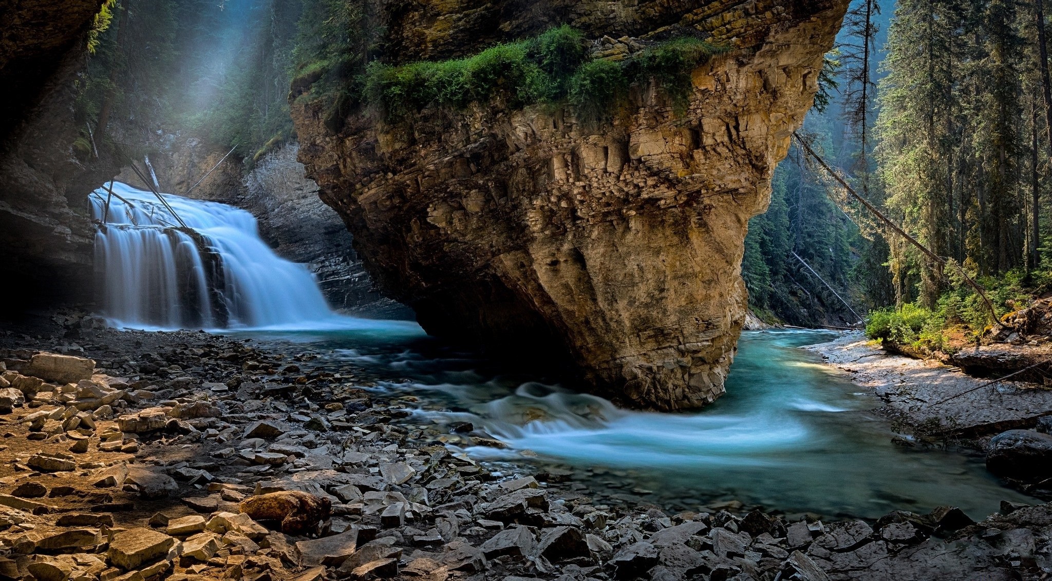 Waterfall flowing through a rocky canyon with trees HD Wallpaper