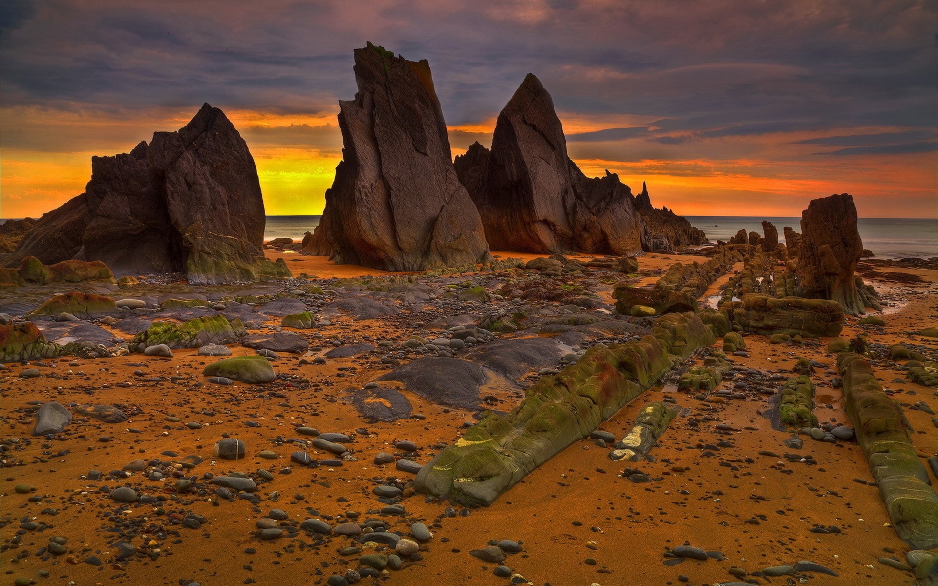 Rocky beach at sunset with dramatic rock formations HD Wallpaper