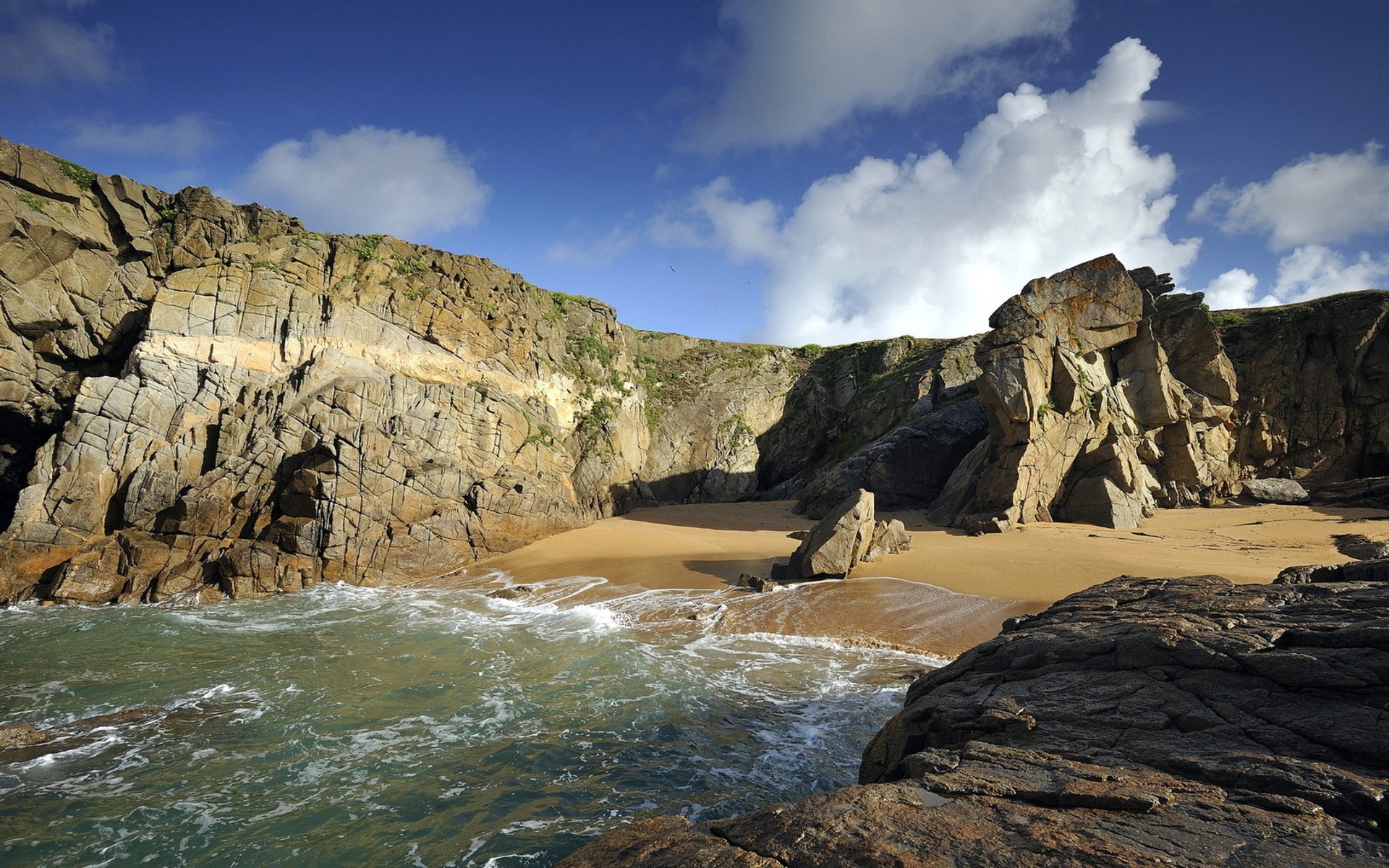 Rocky cove with sandy beach and blue sky HD Wallpaper